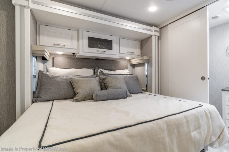 Plush RV rental bedroom features a comfy bed, overhead storage, and modern design, ideal for a relaxing journey.. Coachmen Encore 2022