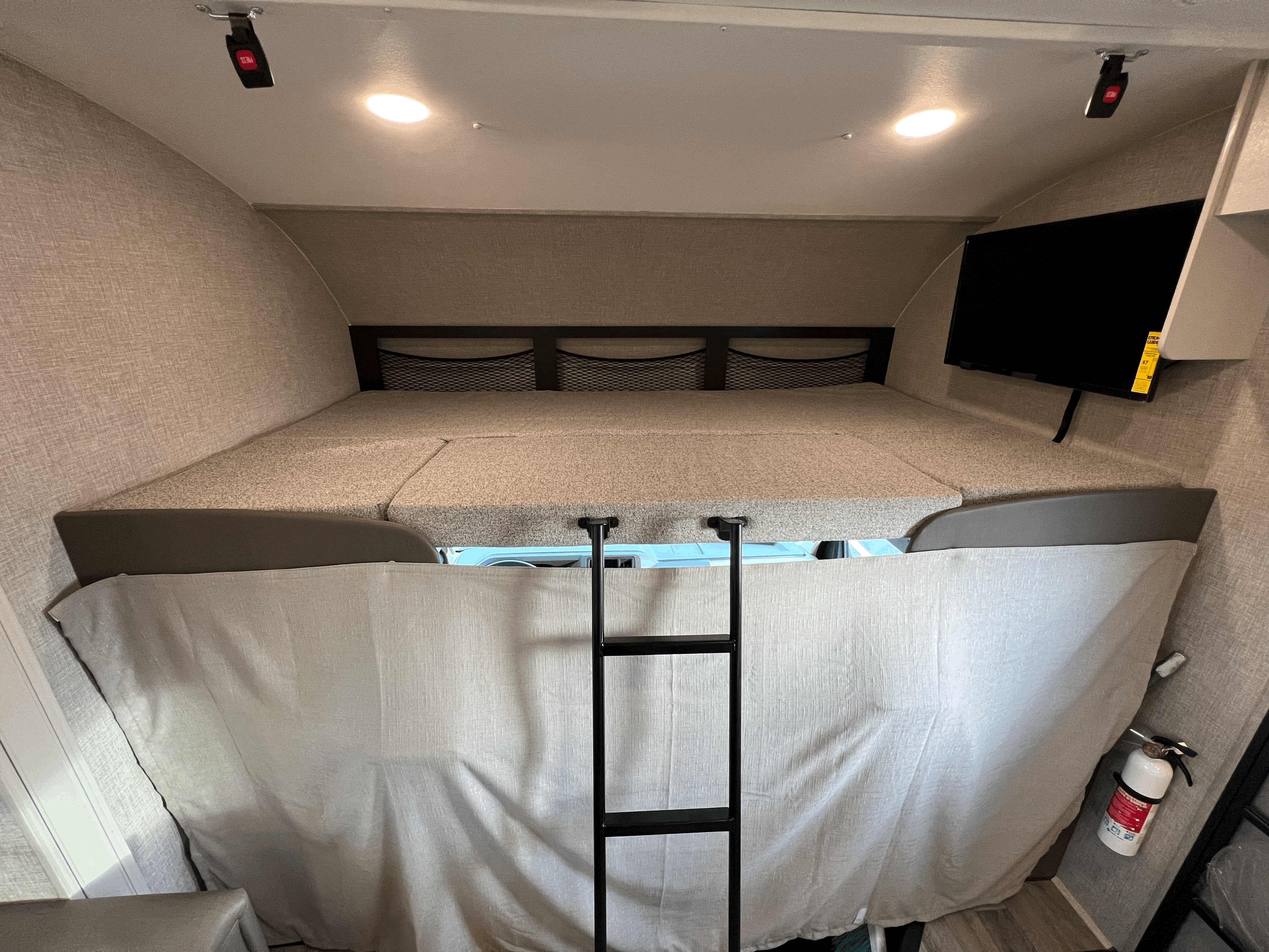 Spacious RV rental bunk bed area with ladder, mounted TV, and fire extinguisher for safety.. Jayco 26XD REDHAWK 2022