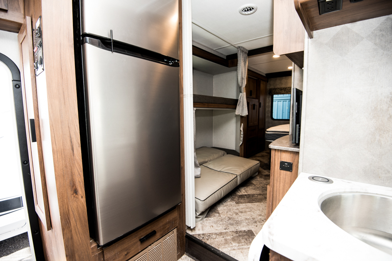 RV rental interior: A stainless steel fridge, bunk beds, kitchen sink, and cozy rear bedroom are visible.. Forest River Sunseeker 2023