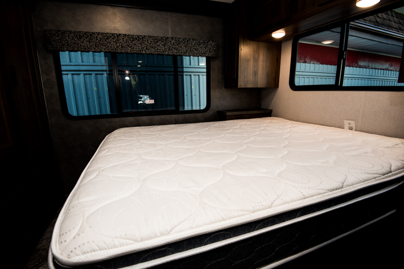 Plush white mattress in a modern RV rental bedroom, complete with ample overhead storage and bright windows.. Forest River Sunseeker 2023