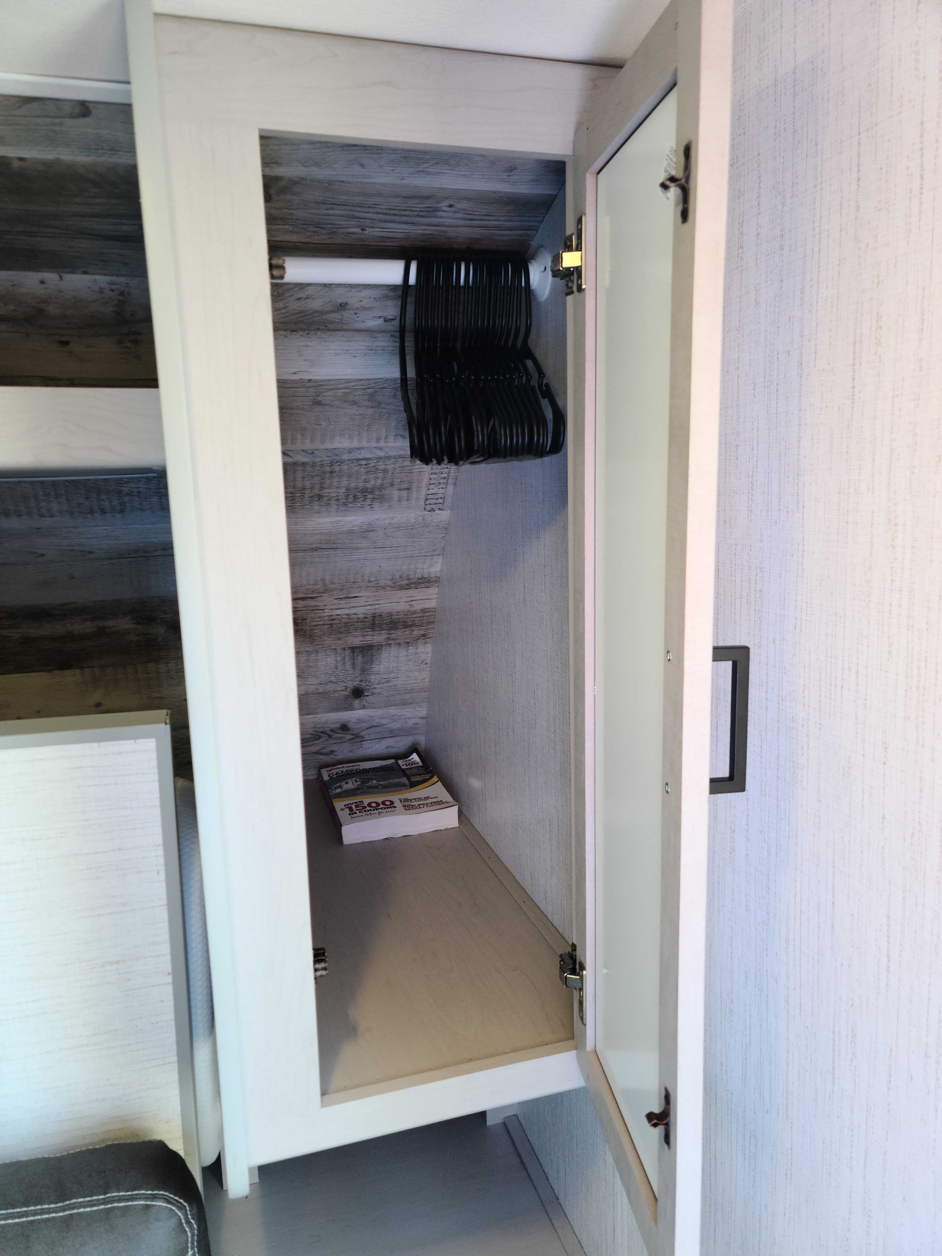 Inside an RV rental closet: hangers, a rod, and lower storage shelf with a book. Perfect for organizing on the road.. Heartland mallard 2022