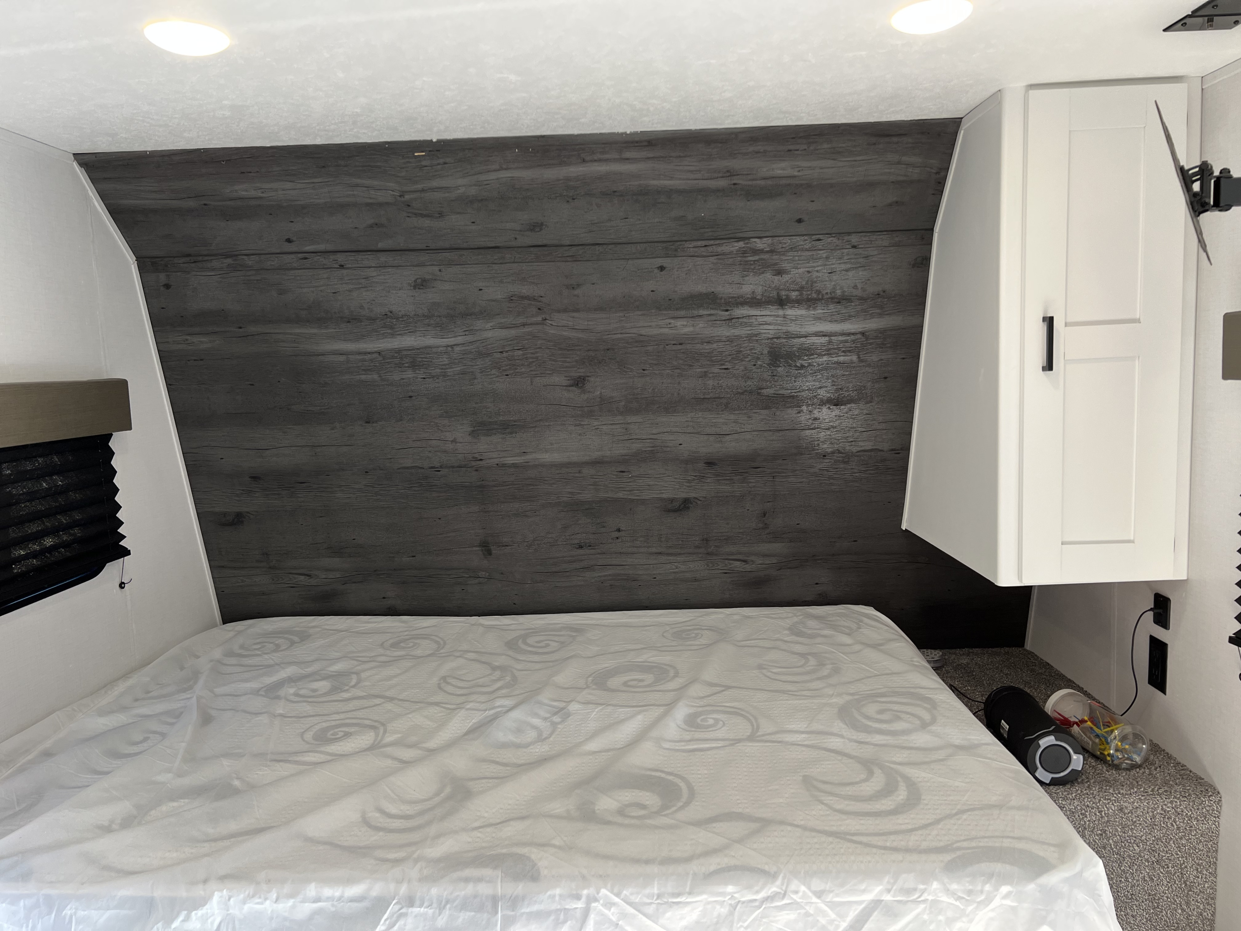 RV rental bedroom featuring a wood-look headboard, white cabinetry, bed, and bright LED lighting. Outlets visible.. Keystone RV Hideout LHS 176 2021