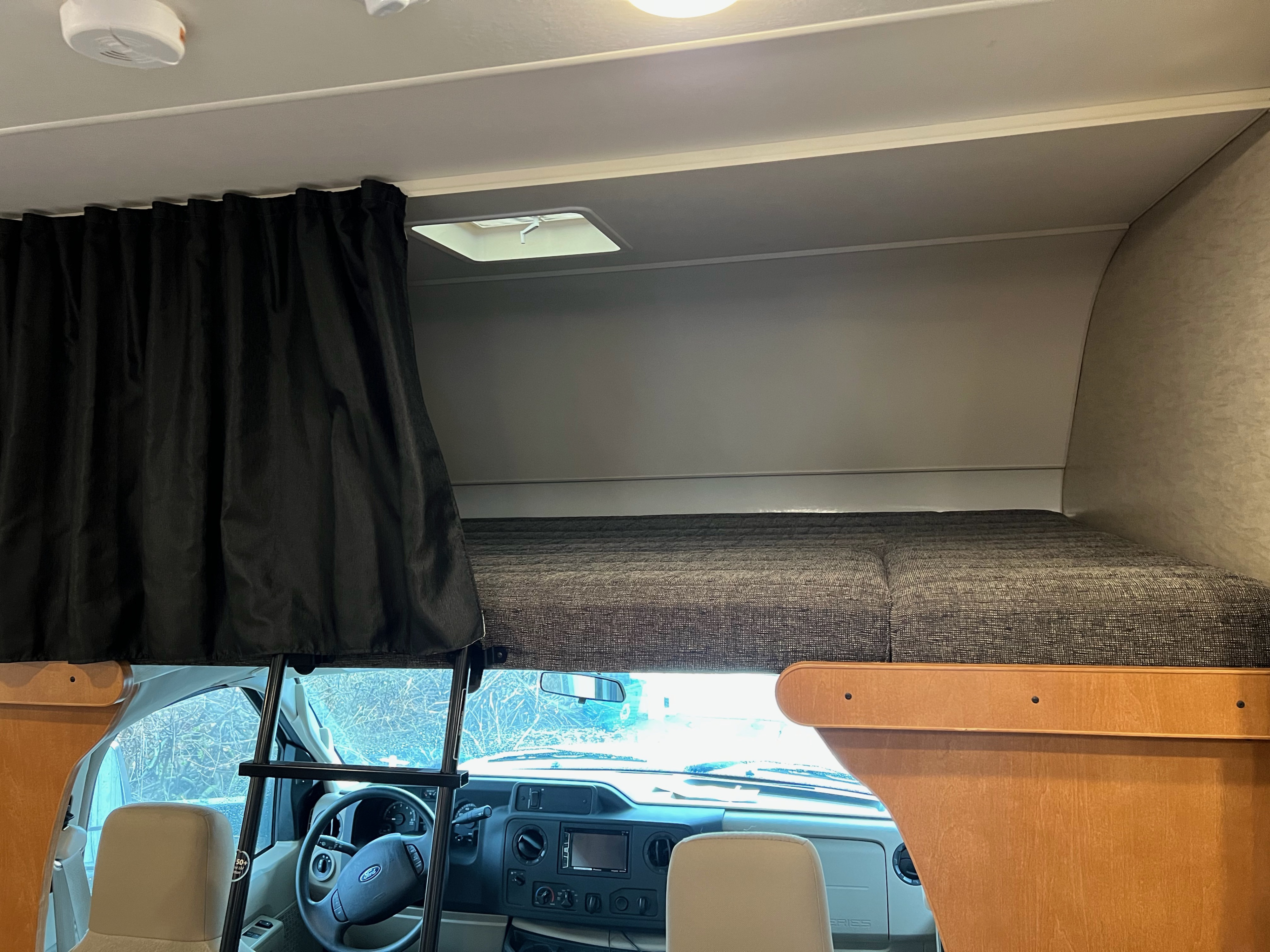 RV rental interior: View of the driver's cabin and a cab-over bunk bed with a ladder and privacy curtains.. Winnebago Minnie Winnie 2017