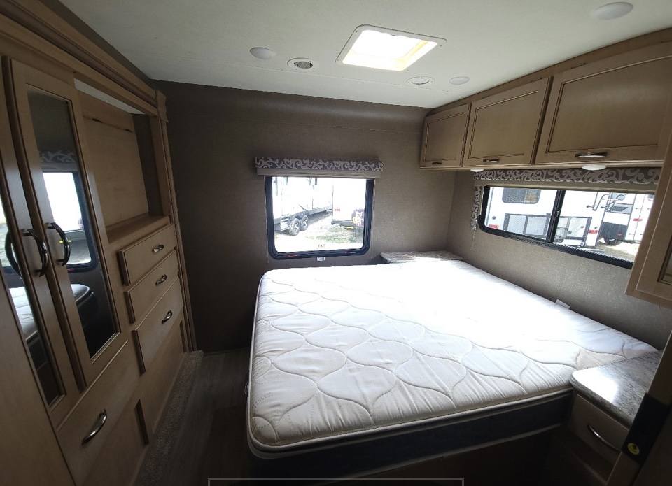 Spacious RV rental bedroom with comfortable mattress, ample storage (cabinets, wardrobe), and bright windows. Perfect for travel.. Thor Four Winds 2020