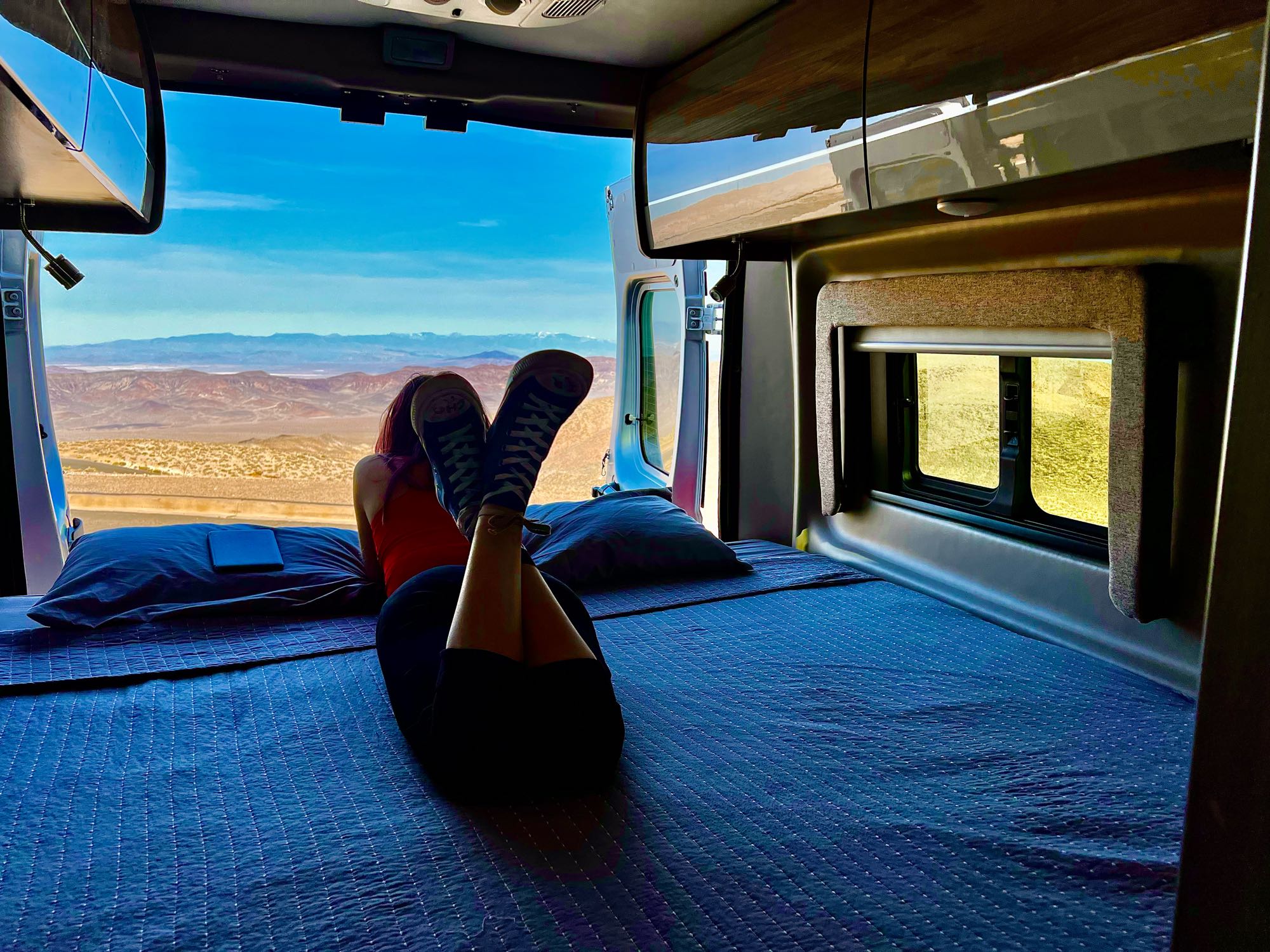 Relaxing in a comfortable RV rental, enjoying vast desert views from the open camper van doors.. Thor Motor Coach Sequence 2022
