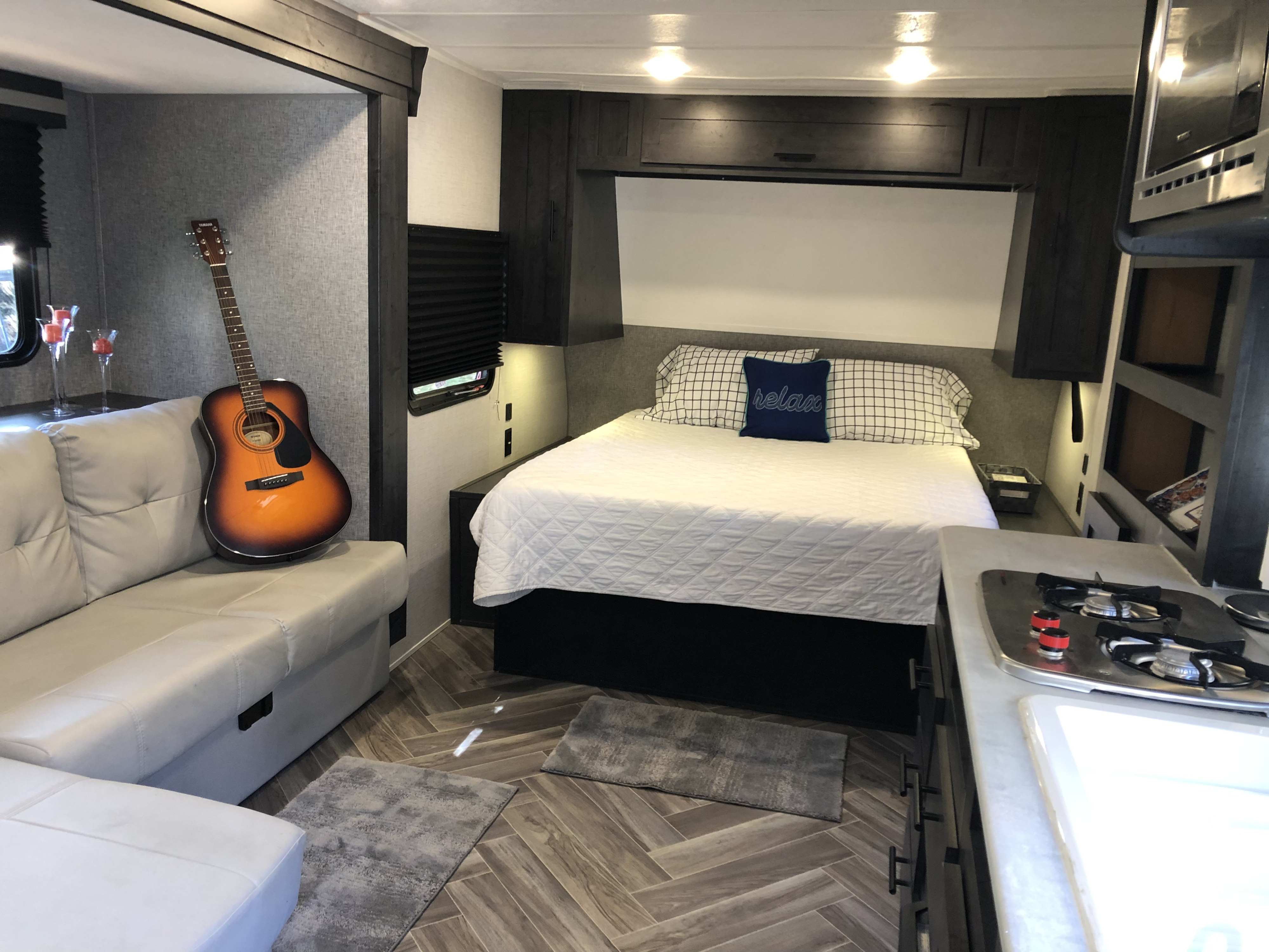 Explore this modern RV rental interior featuring a comfy sofa, bedroom with 'relax' pillow, and functional kitchenette.. Forest River Ozark 1800 QS 2020