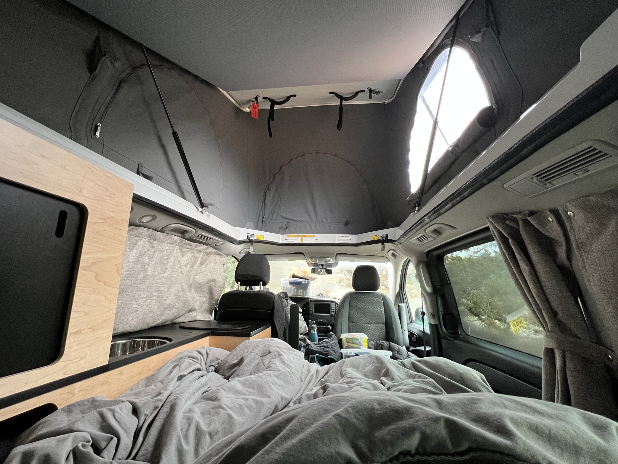 Bright RV rental camper van interior: pop-top roof, cozy bed, and functional kitchen space.. Mercedes-Benz Metris 2021