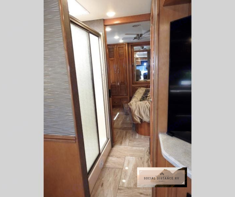Step inside this RV rental, featuring a hallway leading to a cozy bedroom, a modern shower, and a TV.. Thor Motor Coach Venetian 2017