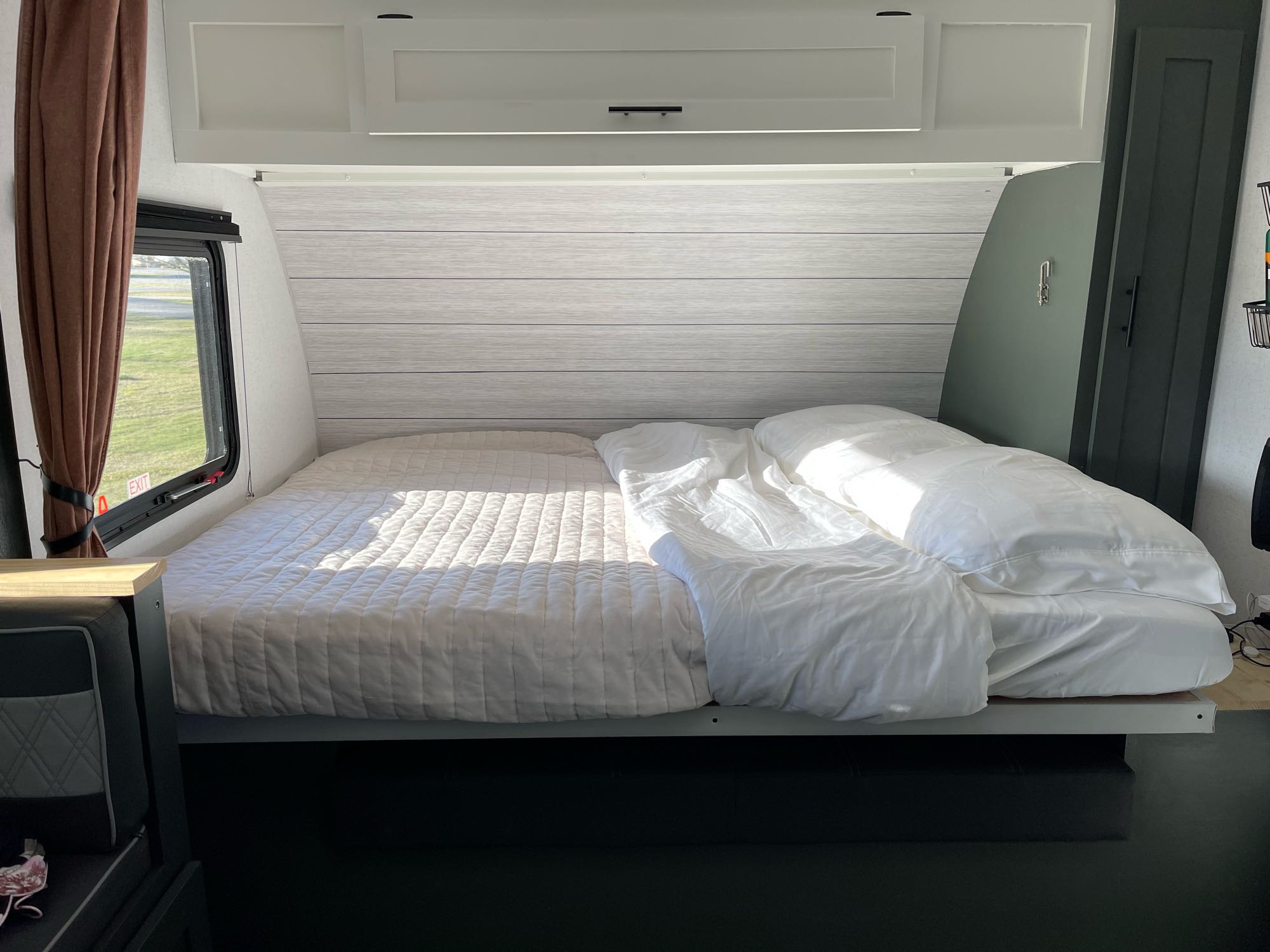 Cozy rv rental bedroom with a sunlit bed & white bedding. Overhead cabinets and a window enhance the travel space.. Forest River 178BHSKX 2022