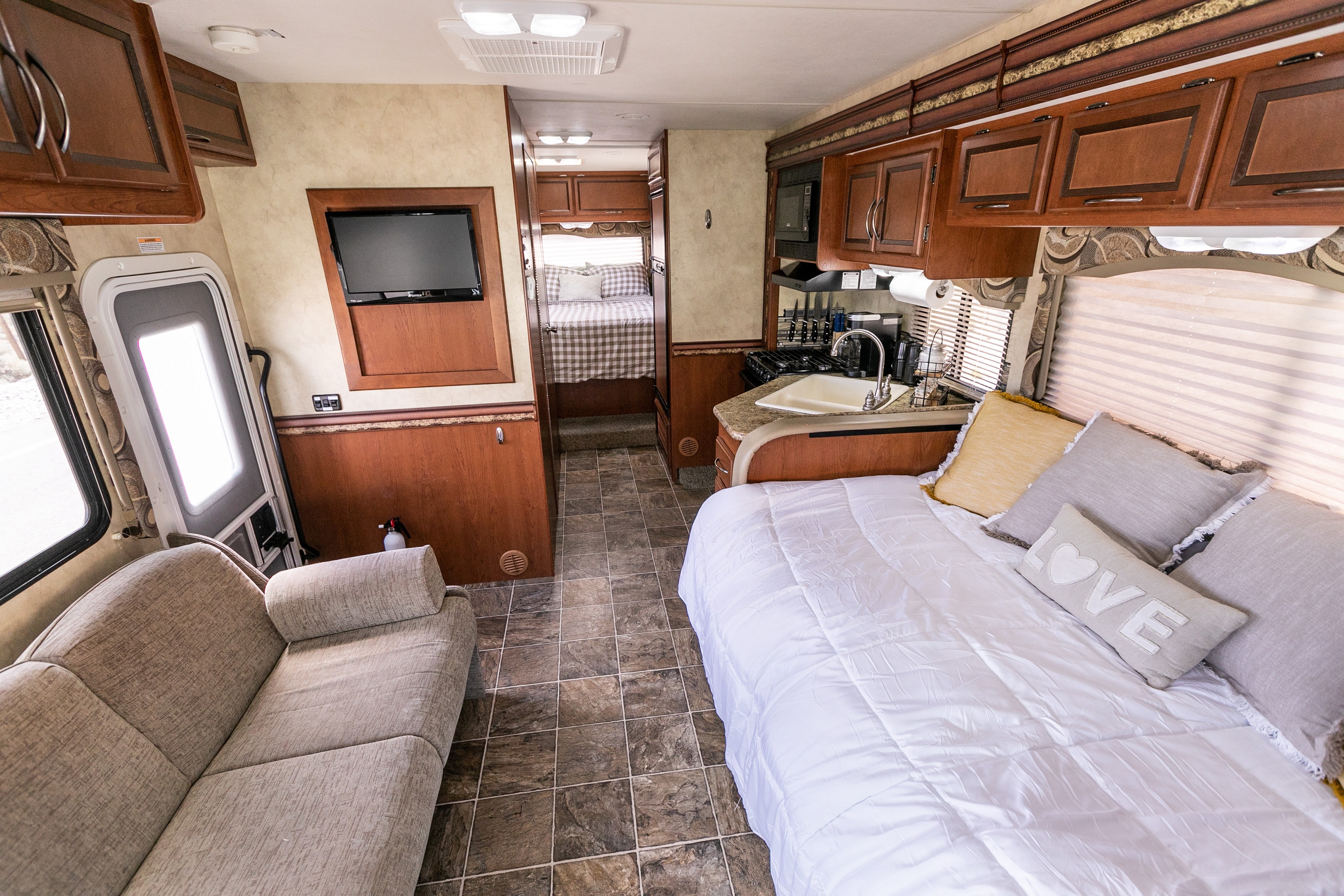 Interior of a modern RV rental: living area with couch, kitchen with sink, plus two sleeping areas. Clean and spacious.. Thor Four Winds 2013