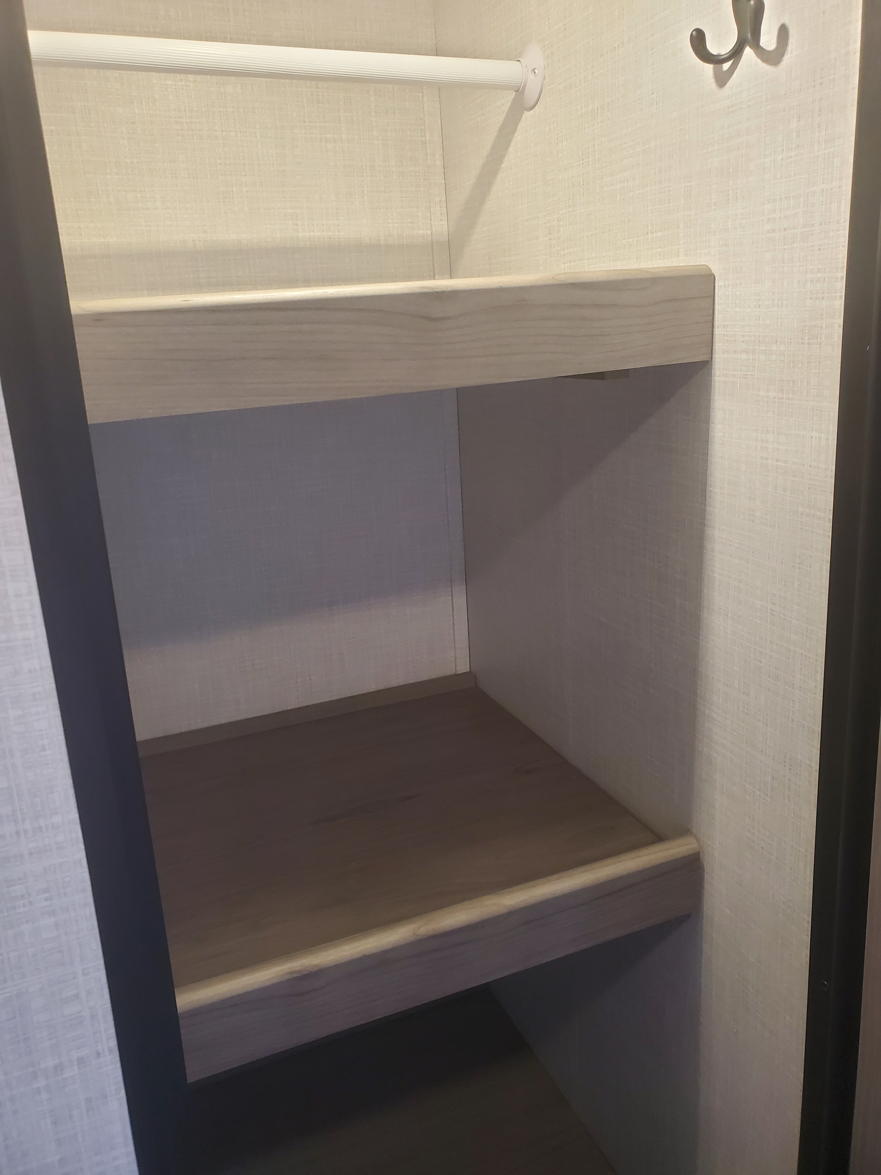 An RV rental closet featuring upper shelves, a hanging rod, and hooks, providing compact, organized storage.. Coleman 2455bh 2022