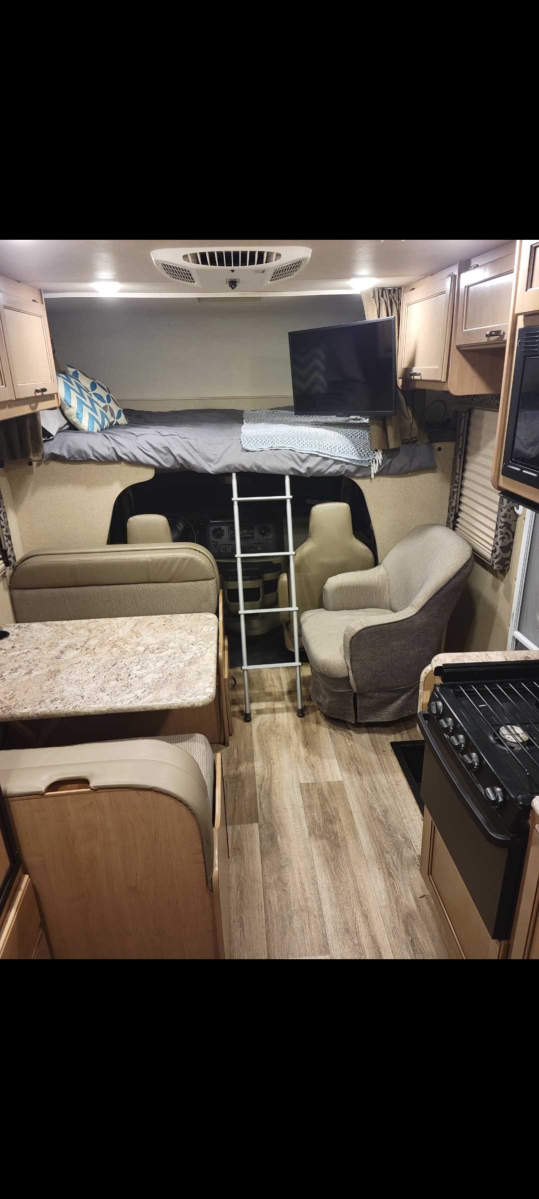 RV rental interior showcasing an overhead bed, dinette, kitchen, and living area with TV.. Thor Motor Coach Four Winds 2019