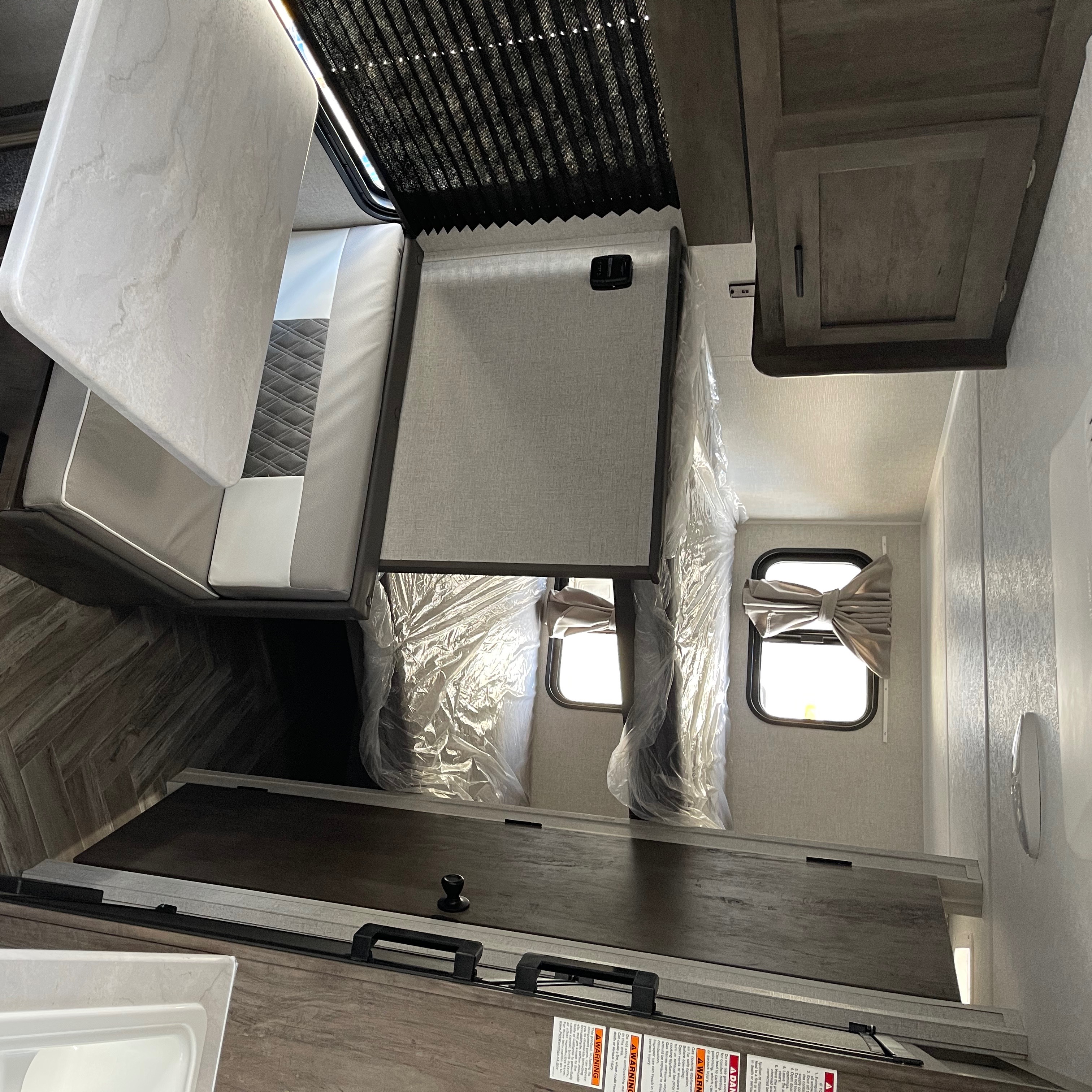 RV rental interior: modern dinette, kitchen counter, and plastic-wrapped bunk beds, ready for travel.. Forest River Salem 179 2021
