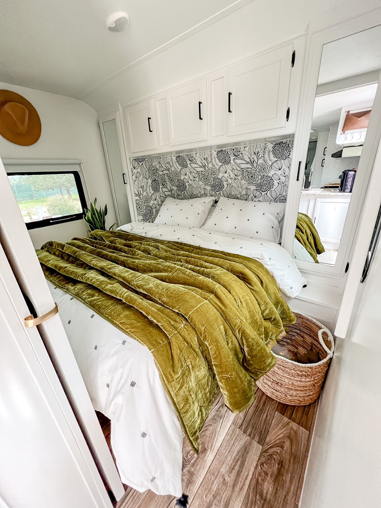 Inside an RV rental: a stylish bedroom with a plush green velvet comforter, floral accent wall, and clever storage.. Keystone RV Passport Grand Touring 2017