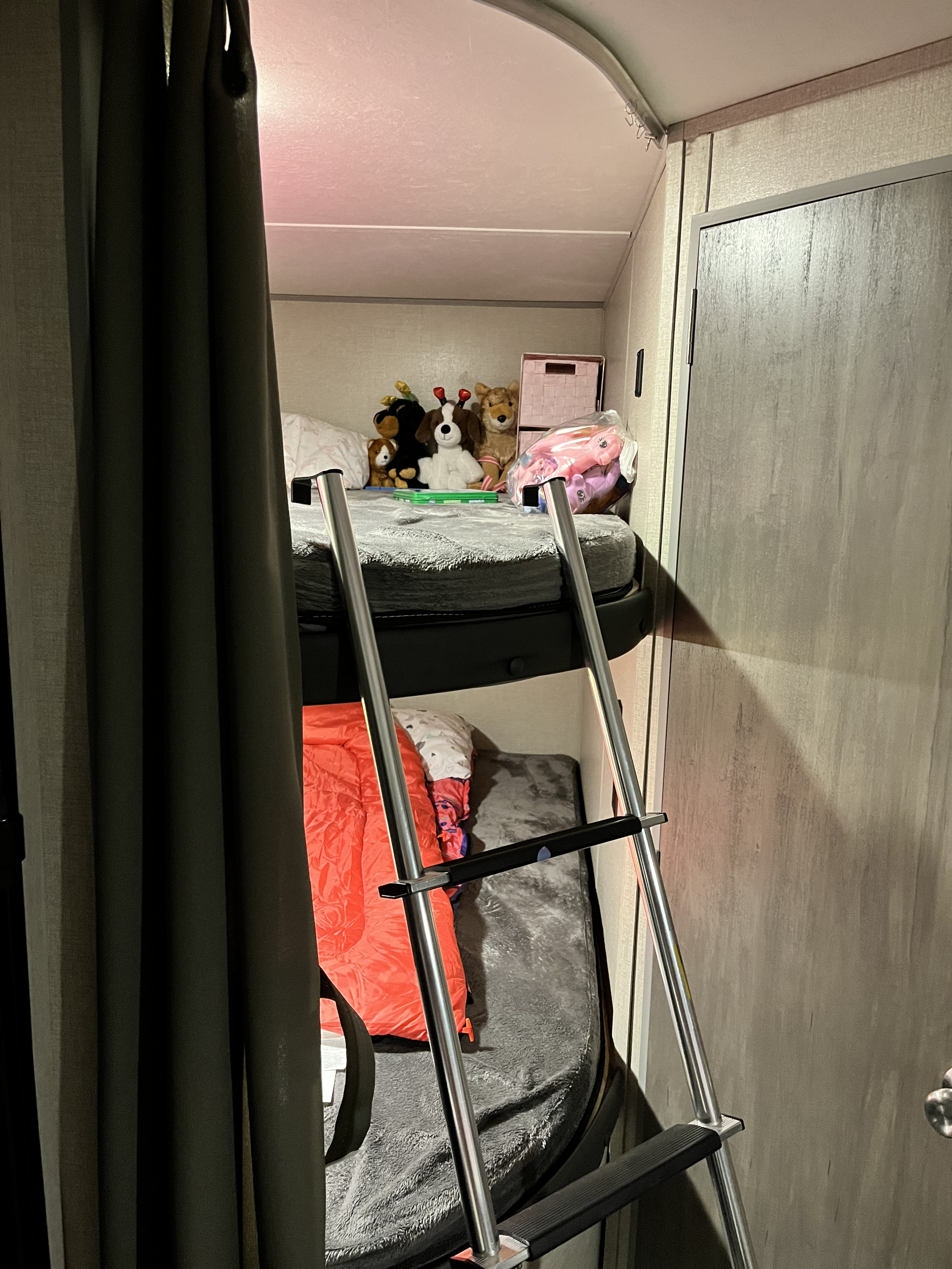 Inside an RV rental, showing the cozy bunk bed area with a ladder, soft blankets, and several stuffed animals on the top bunk.. Forest River Catalina Summit 184BHS 2022