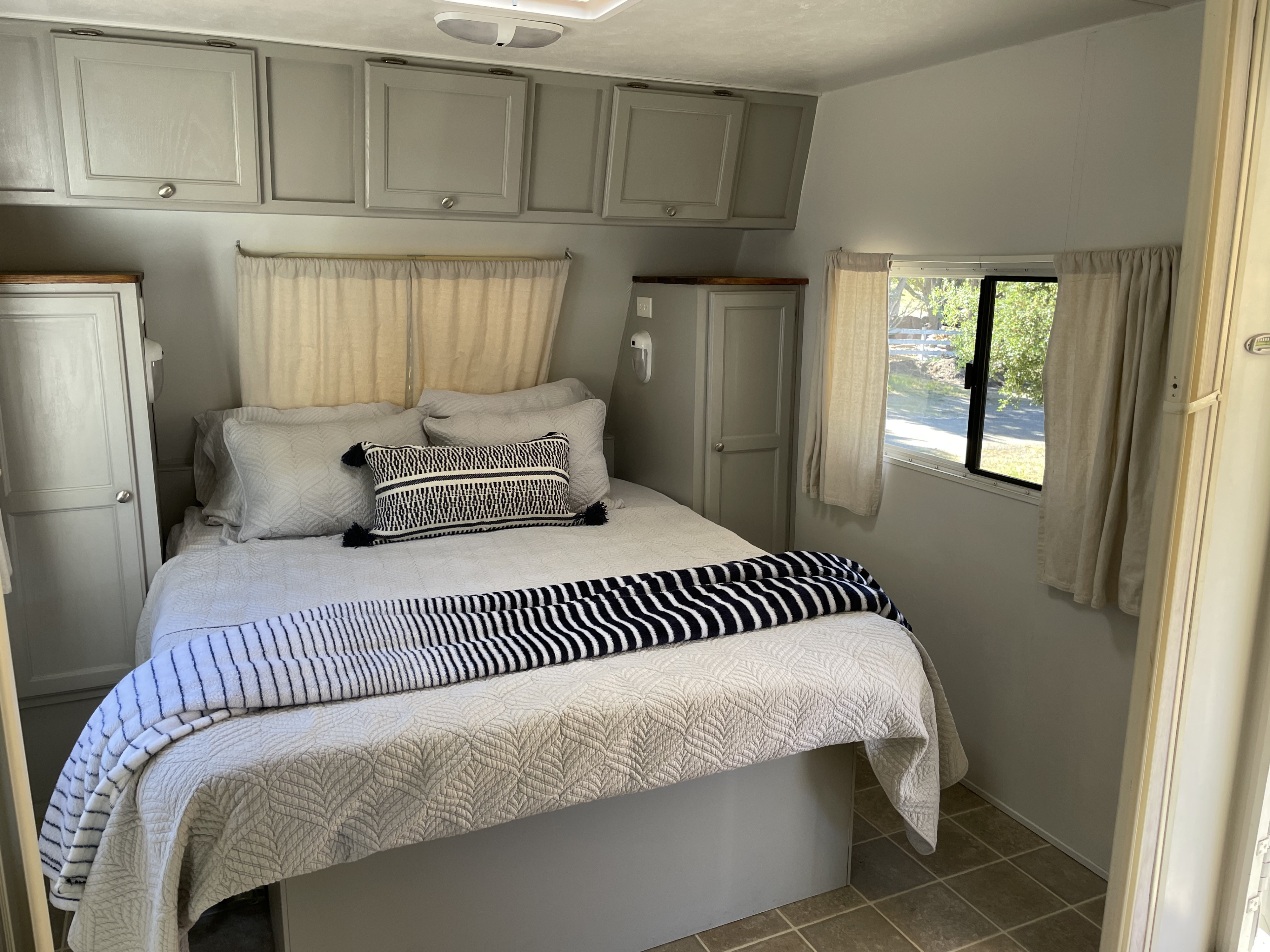 Cozy RV rental bedroom featuring a comfortable bed, light gray cabinets, and a window with natural light.. R-Vision Trail-Lite Trail-Cruiser 2004