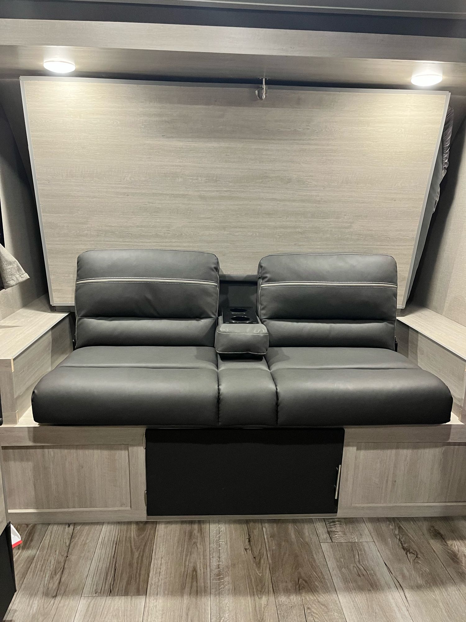 RV rental: Modern interior featuring dark grey convertible sofa with cup holders, wood panel wall, and floor storage.. Forest River Catalina Summit 184BHS 2022