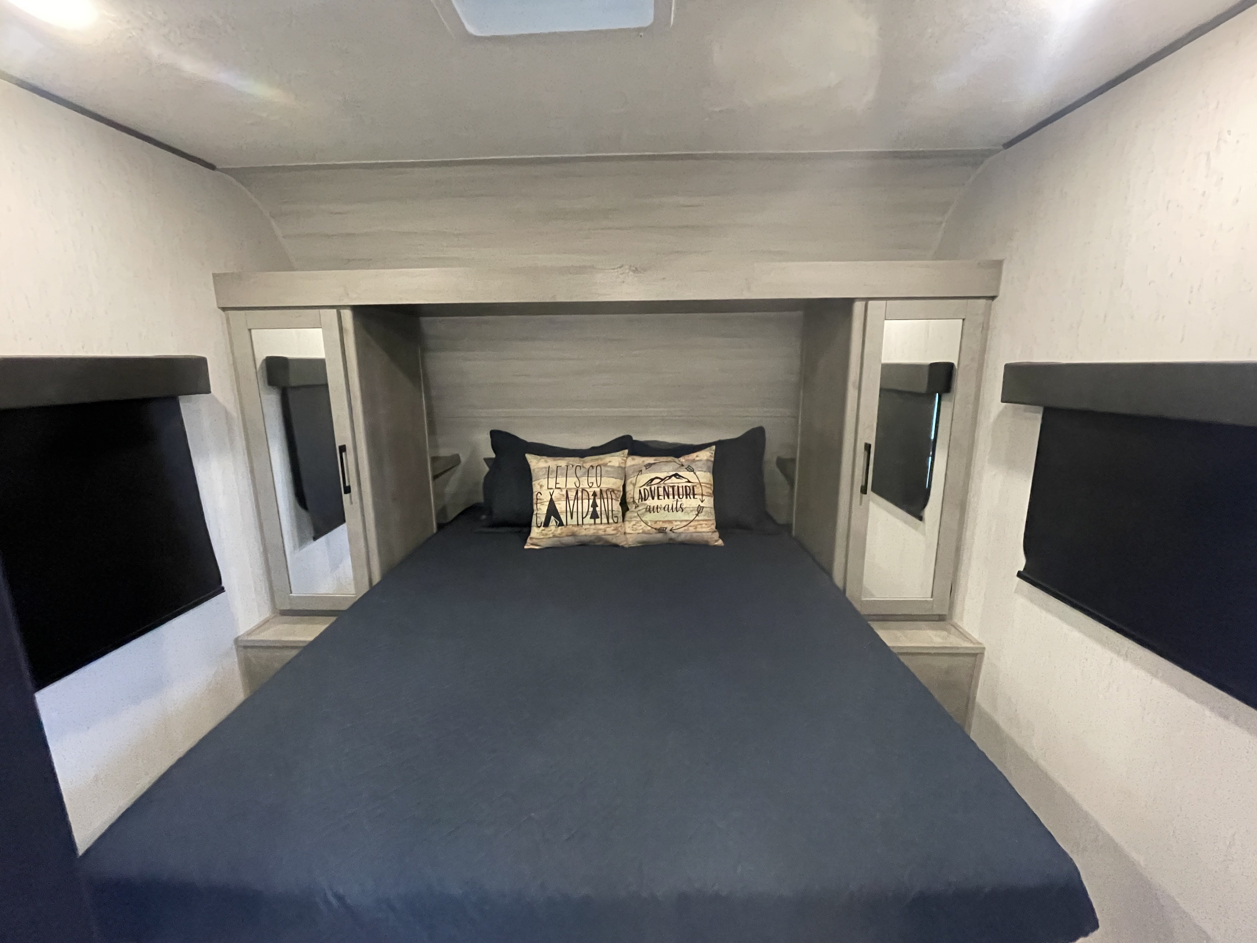 Comfortable RV rental bedroom featuring a queen bed with adventure pillows, mirrored wardrobes, and blackout blinds.. Dutchman Kodiak SE 2022