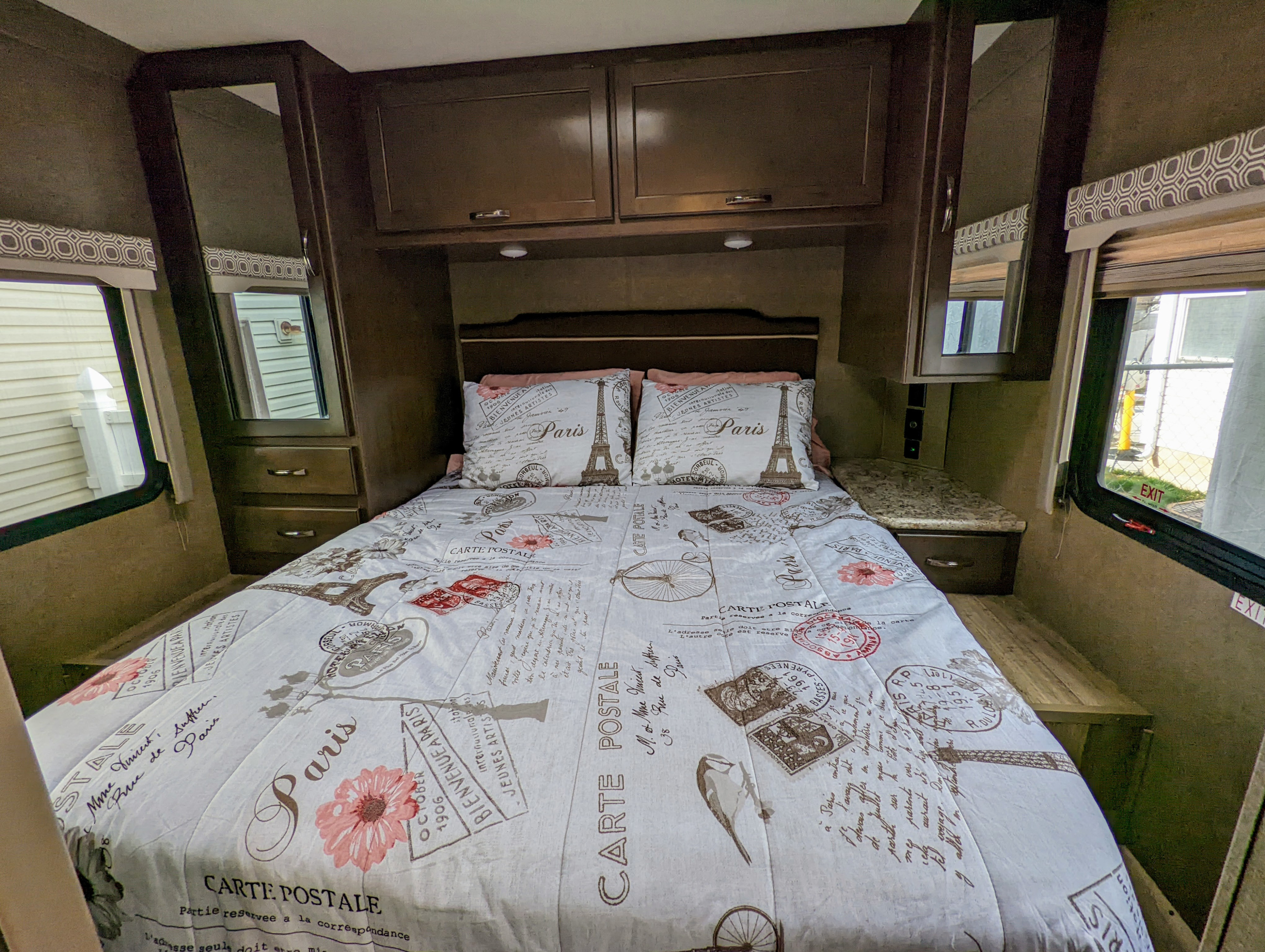 Cozy RV rental bedroom with Paris-themed bedding, compact storage, and windows.. Thor Four Winds 2020