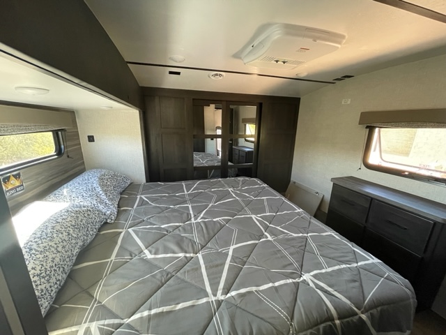 Spacious RV rental bedroom with a cozy king bed, built-in storage (dresser, wardrobe), and AC for comfort.. Crossroads RV Cruiser Aire 2021