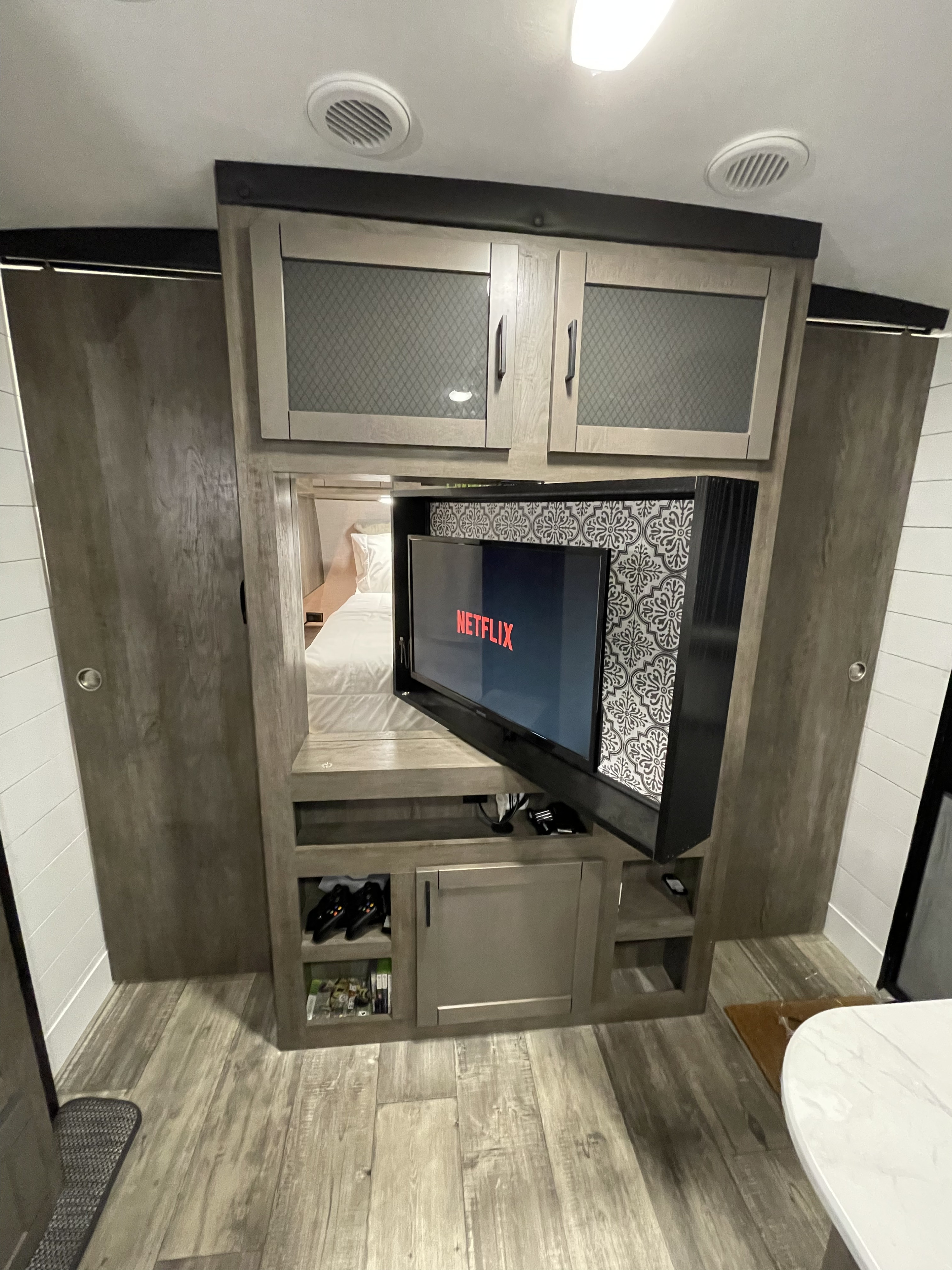 Modern RV rental living space with a swivel Netflix TV, storage, and view into the connecting bedroom.. Heartland RVs North Trail 2021