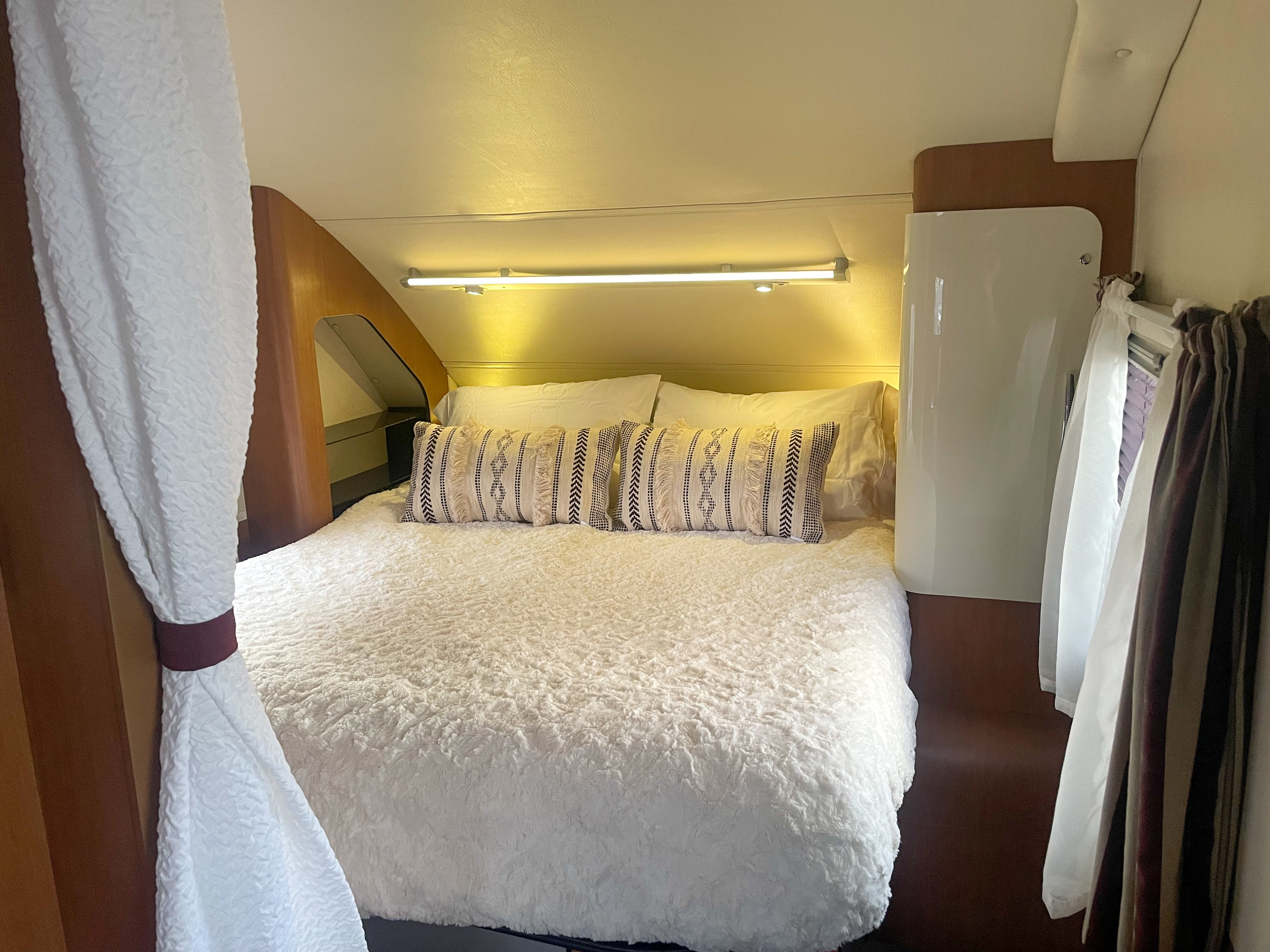 Relax in this inviting RV rental bedroom, featuring a soft bed, textured bedding, and bright lighting.. Evergreen Element 2013