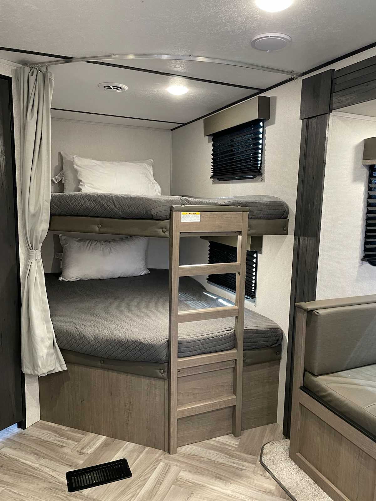 Inside this RV rental, dual bunk beds with ladder and privacy curtain offer cozy sleeping. Ideal for family trips.. Keystone RV Hideout 2021