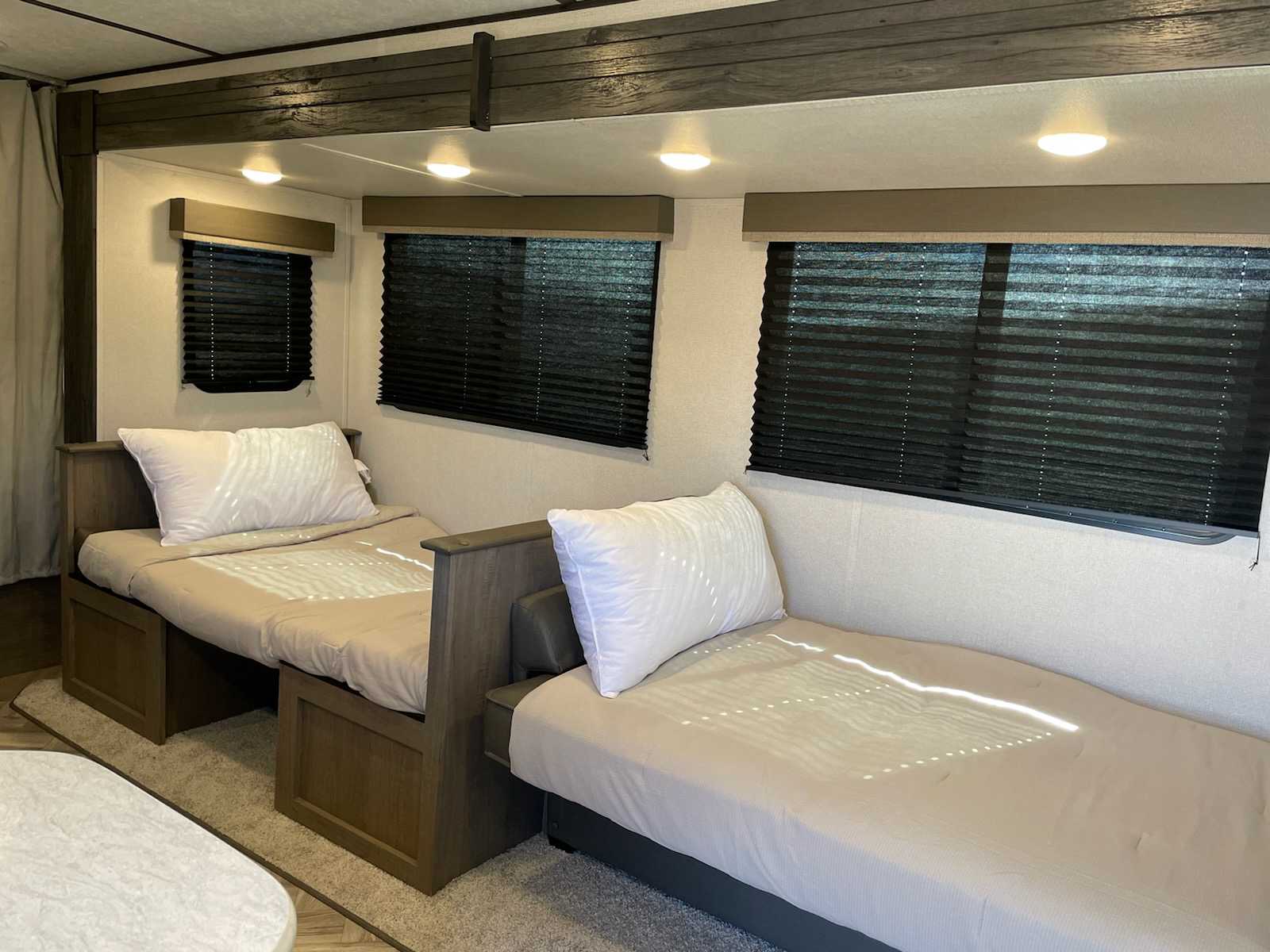 Cozy RV rental interior featuring two twin beds, white pillows, and windows with dark blinds for a restful sleep.. Keystone RV Hideout 2021