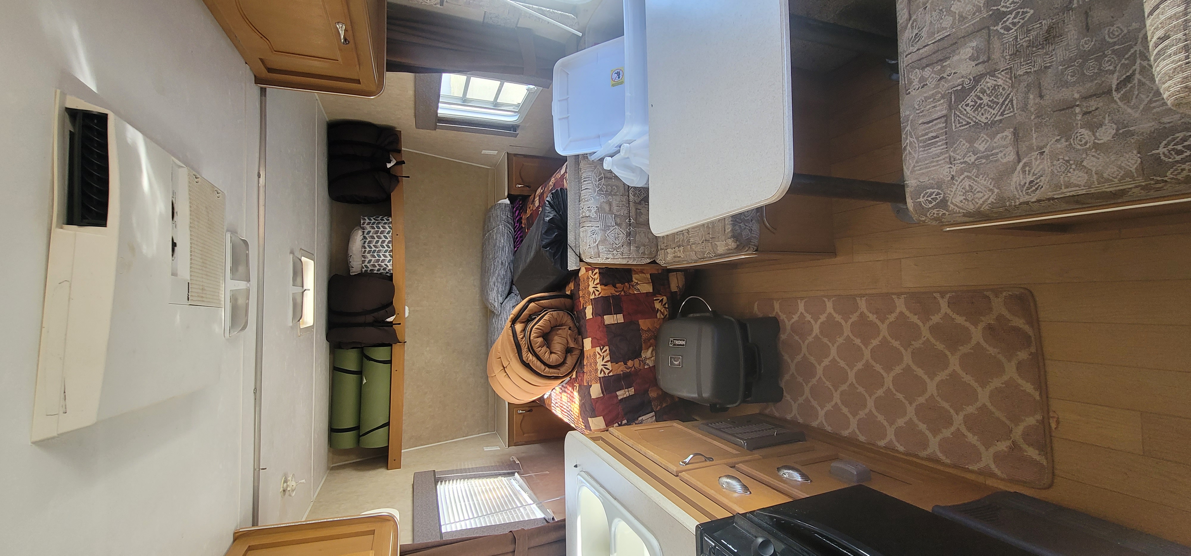 Interior of an RV rental, showcasing a compact living space, packed with sleeping bags, mats, and a small kitchen.. Gulf Stream Ameri-Lite 2006