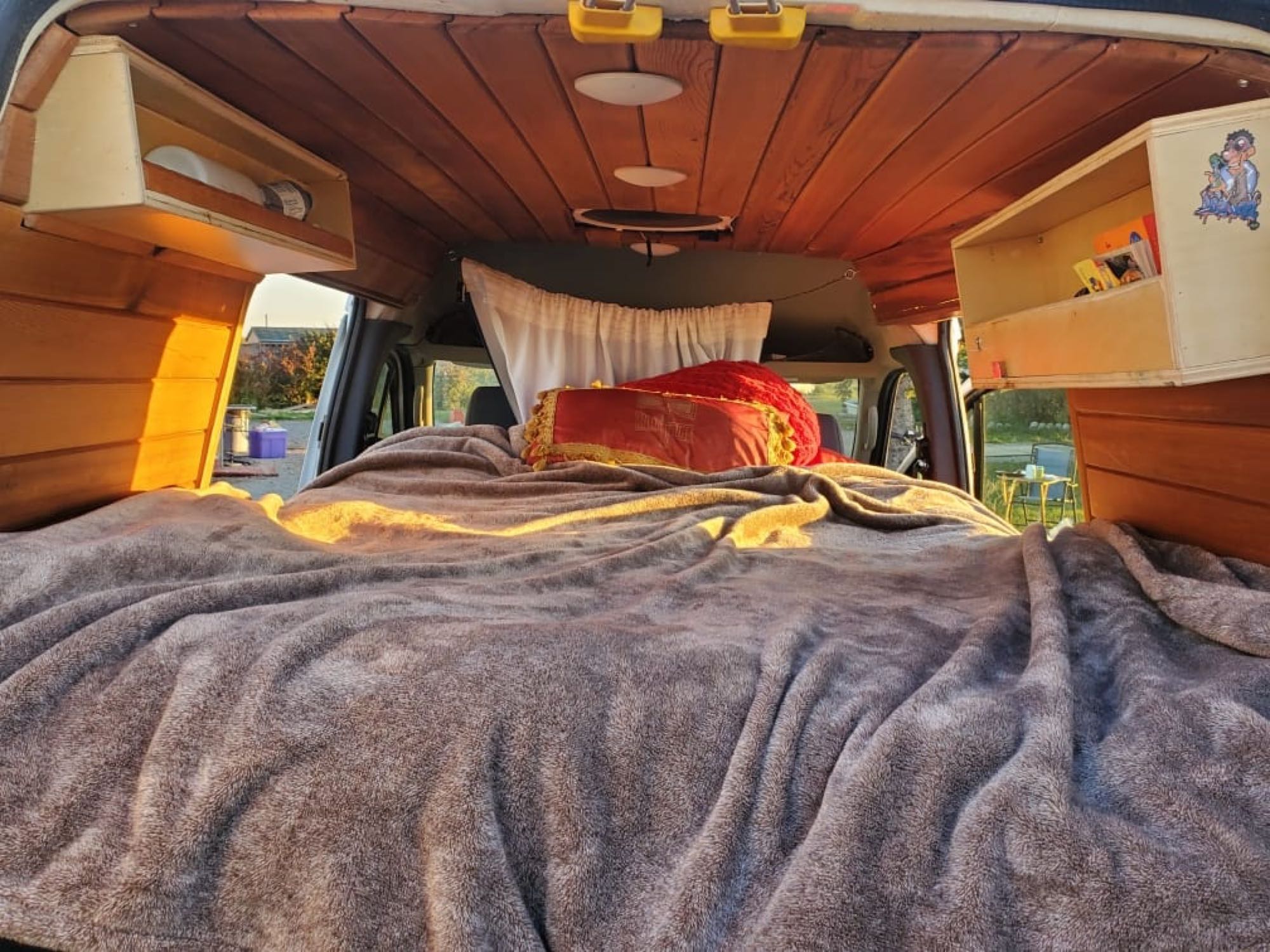 Spacious rv rental interior featuring a comfy bed, wood-paneled ceiling, and convenient storage.. Ford Transit 2010