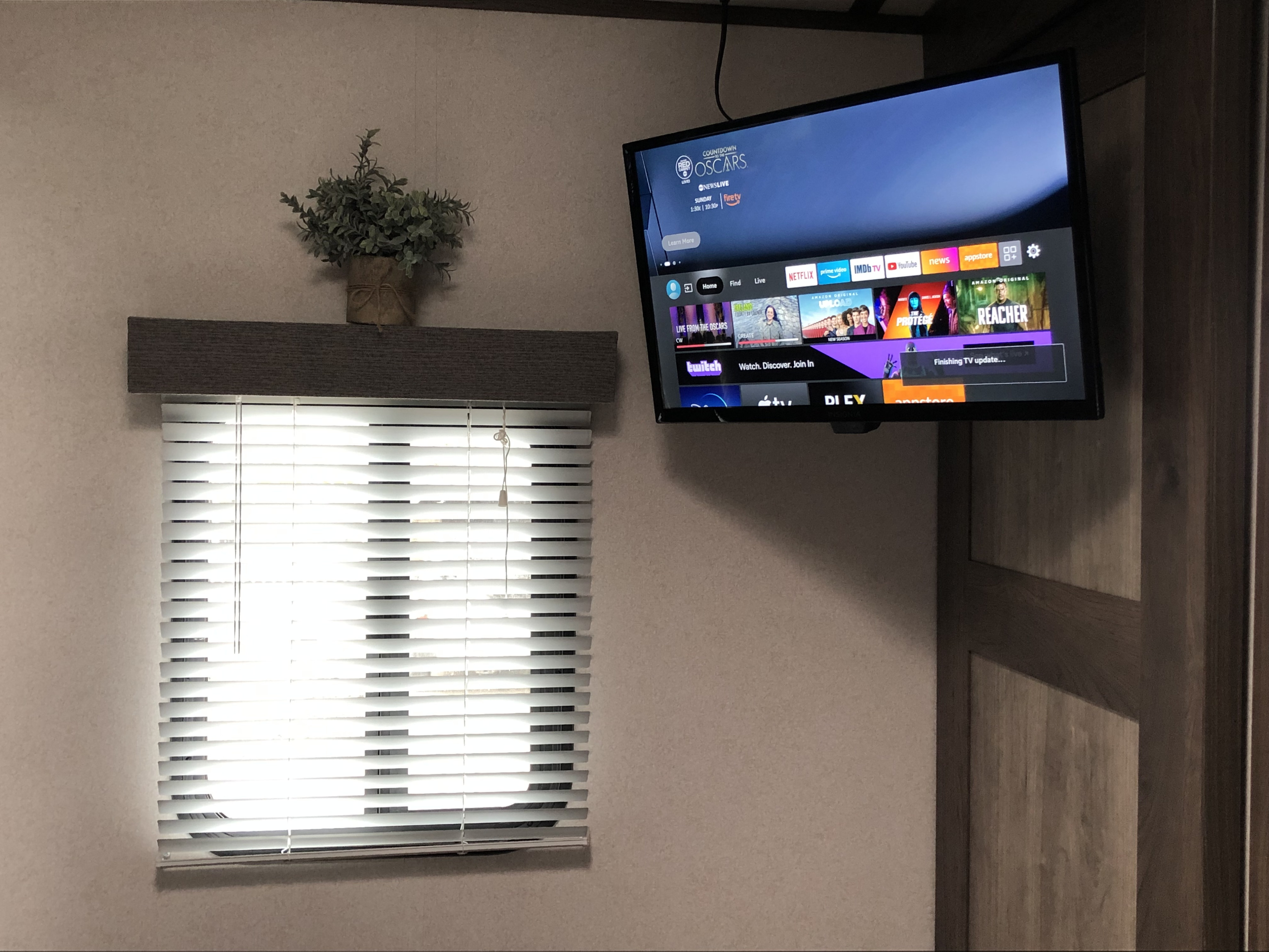 Cozy RV rental interior with a wall-mounted smart TV displaying streaming apps and a window with blinds below.. Keystone RV Passport GT 2021