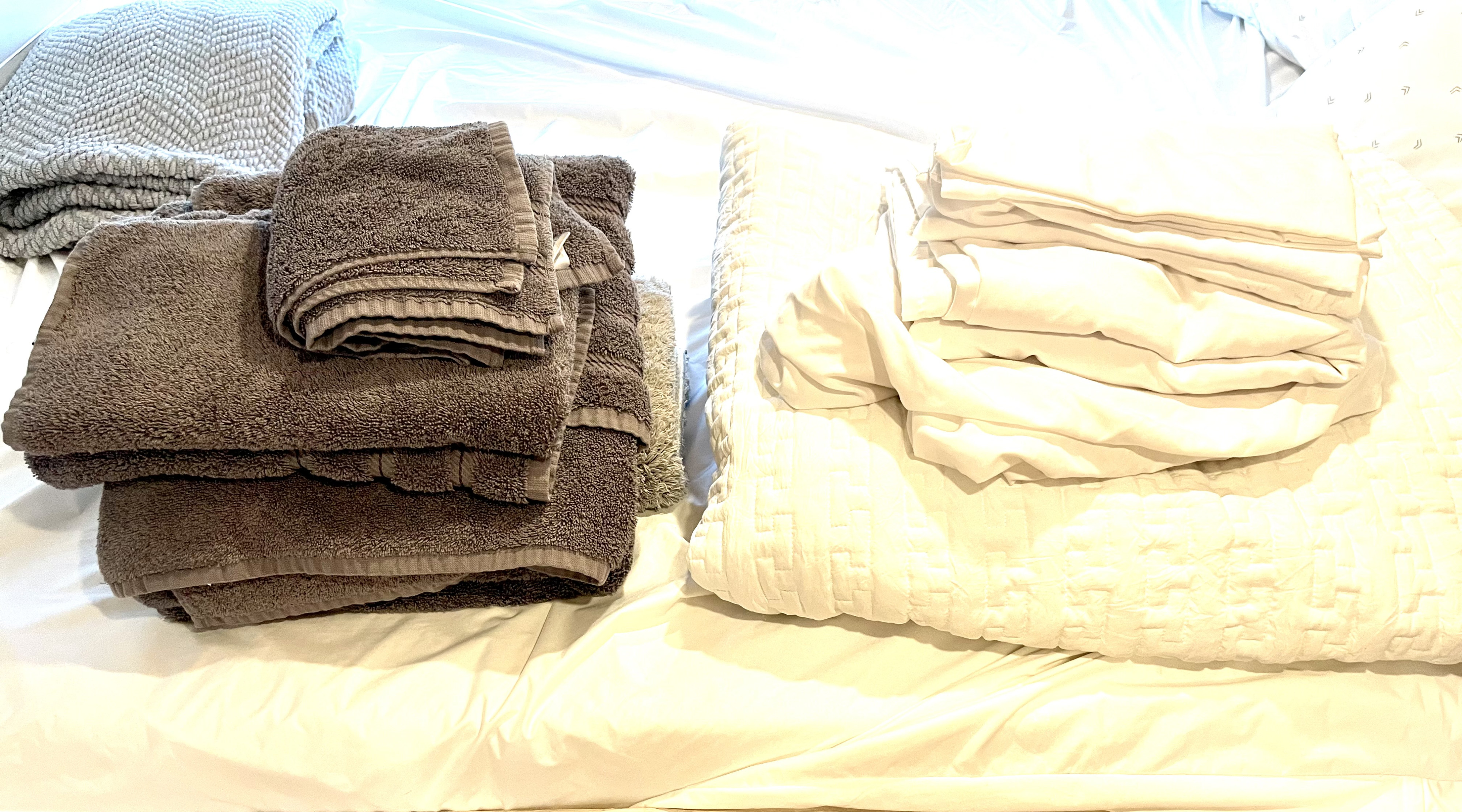 Clean brown towels, a grey blanket, and white bed linens, neatly folded and ready for your RV rental.. Dodge Ram Promaster 2500 2017