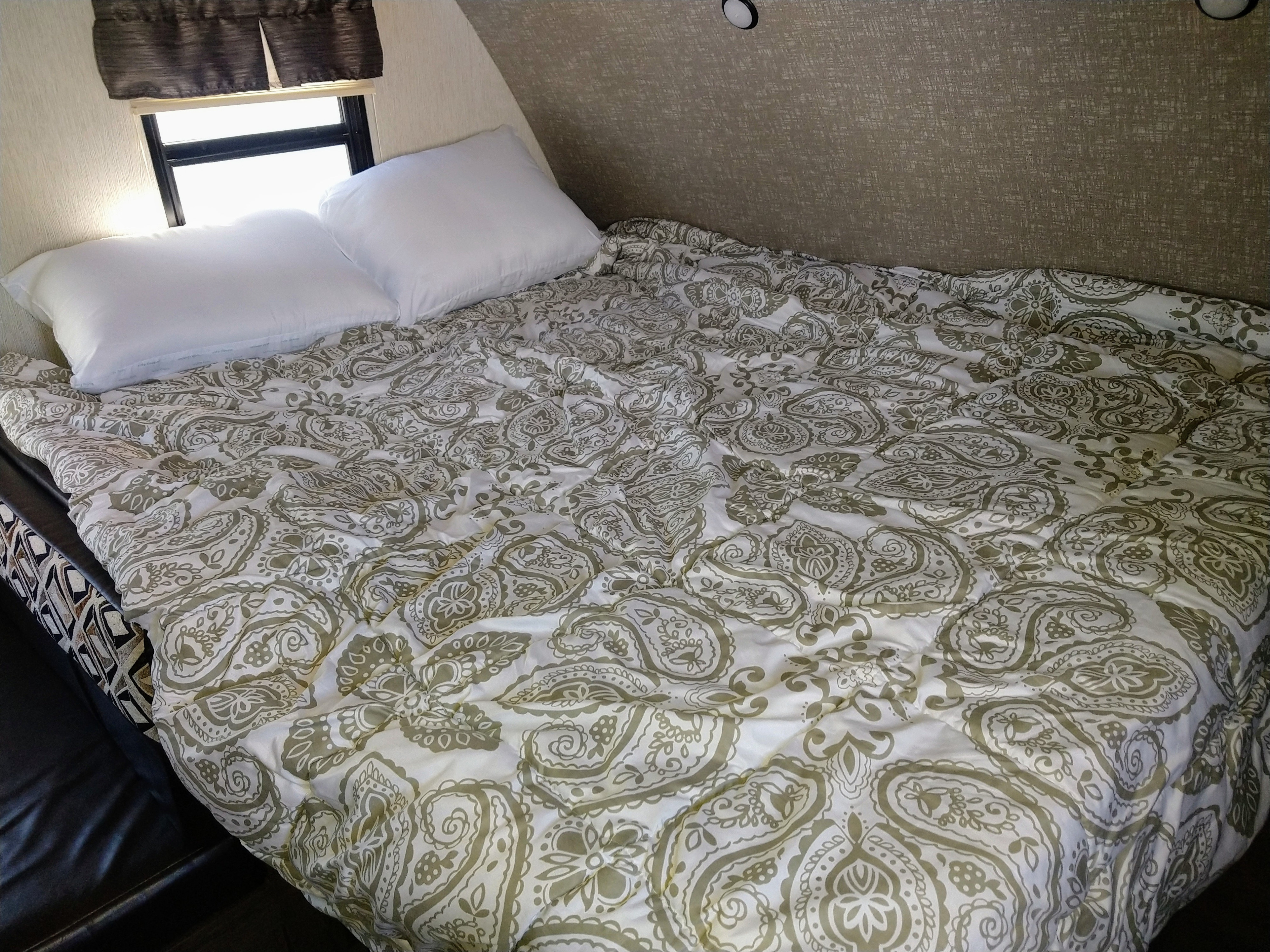 Cozy RV rental bedroom featuring a comfy bed with white pillows and a paisley comforter near a window.. Heartland Mallard M185 2019