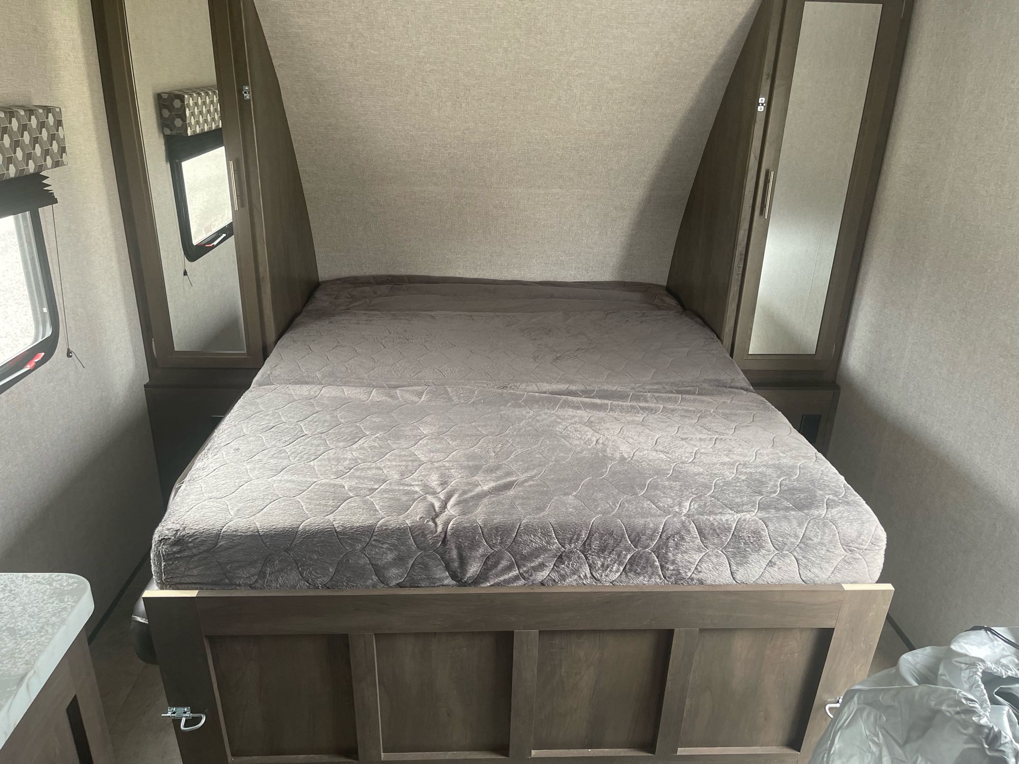 Cozy RV rental bedroom featuring a grey bed, mirrored closet, and window for comfortable travel.. Keystone RV Light LX 2125BH 2021