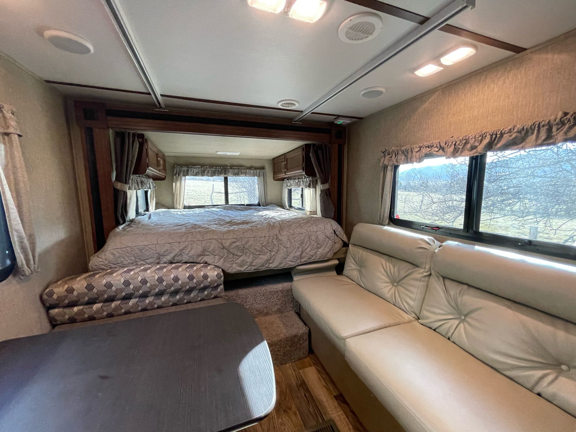 Spacious RV rental interior featuring a comfortable bed, sofa, and dining table, perfect for your next adventure.. Keystone RV Outback Ultra-Lite 2017