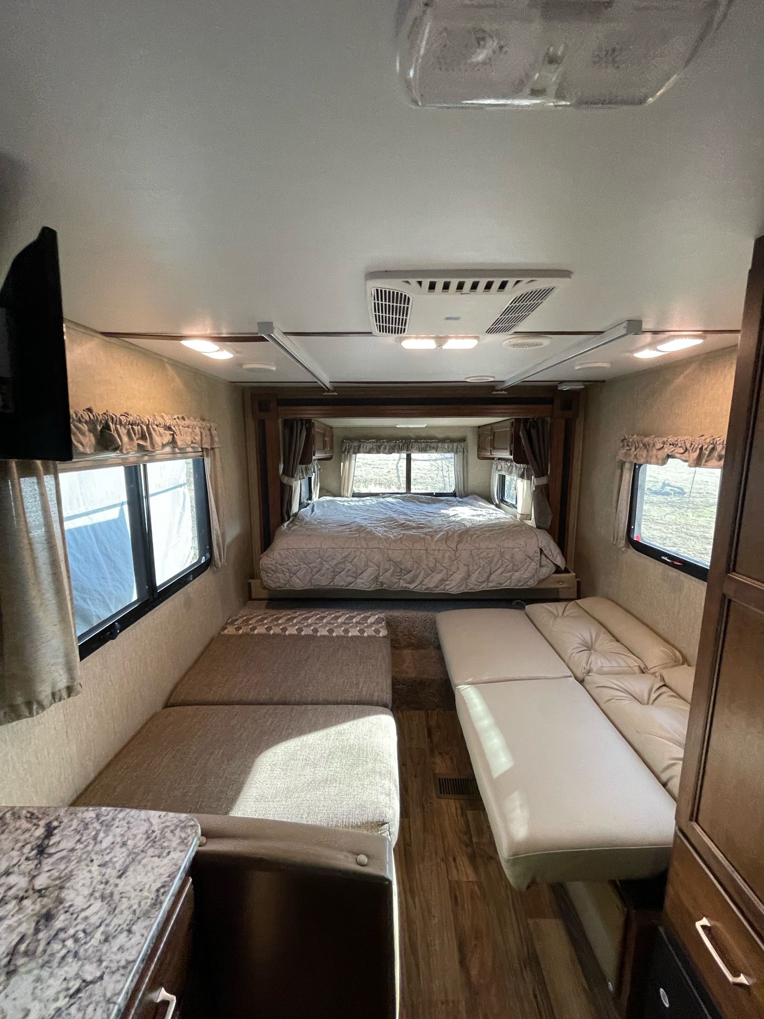 Spacious RV rental interior featuring a comfortable bed, large windows, and flexible living area with sofa seating.. Keystone RV Outback Ultra-Lite 2017