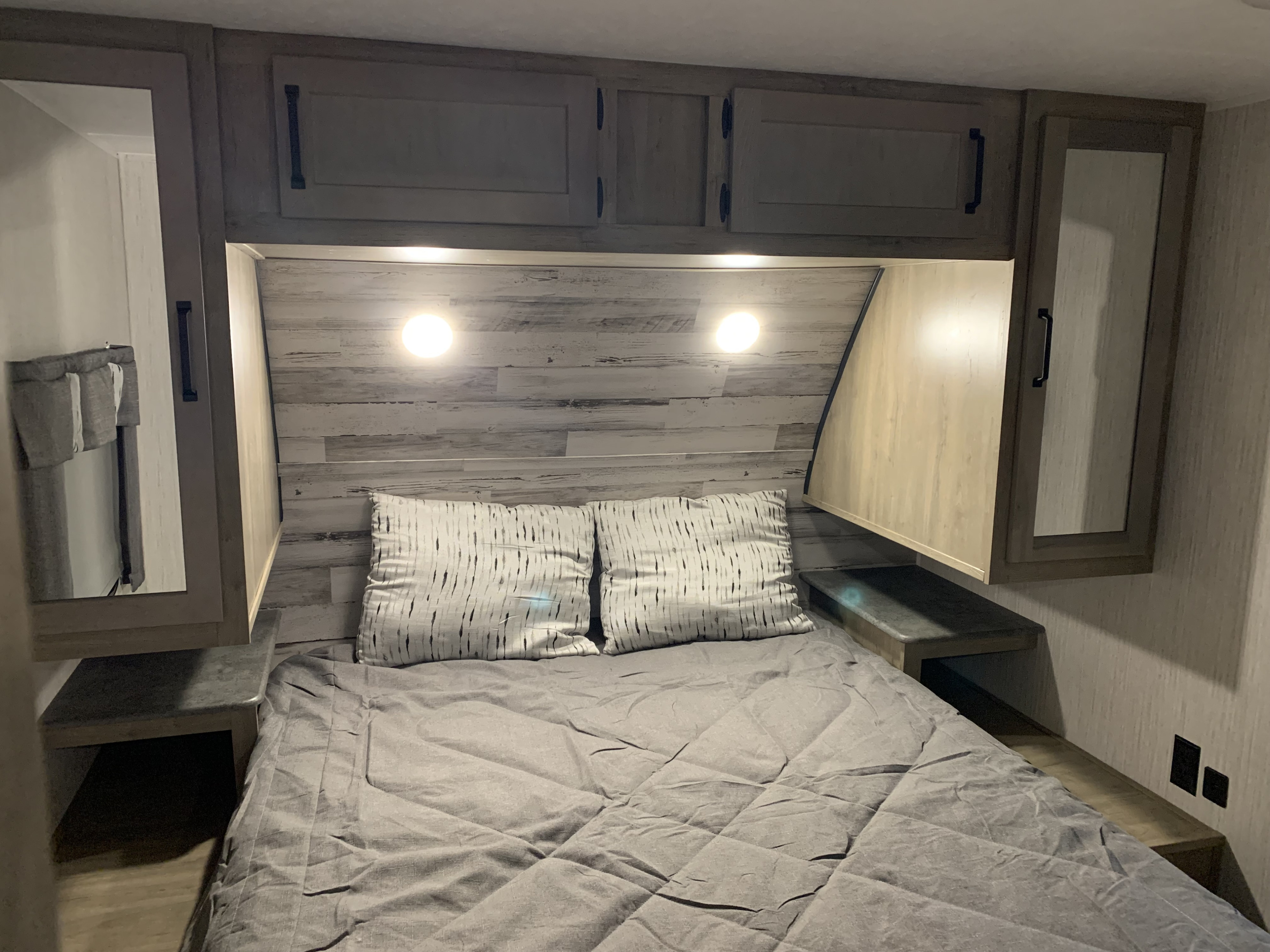 RV rental bedroom: comfy bed, reading lights, overhead cabinets, and mirrored side storage.. Palomino Puma 2022