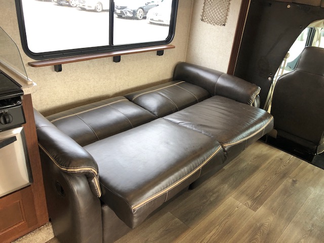 RV rental interior: cozy brown leather sofa bed, window shelf, and cooktop. Perfect for travel.. Forest River Forester 2017