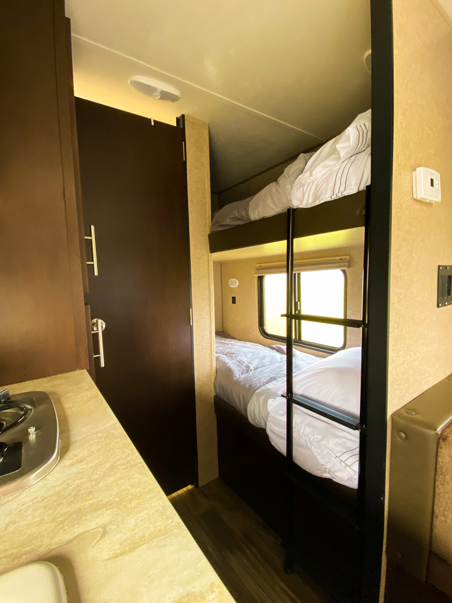 RV rental interior featuring comfortable bunk beds, a compact kitchen counter, and a functional door.. Forest River Cherokee Wolf Pup Cascade 2017