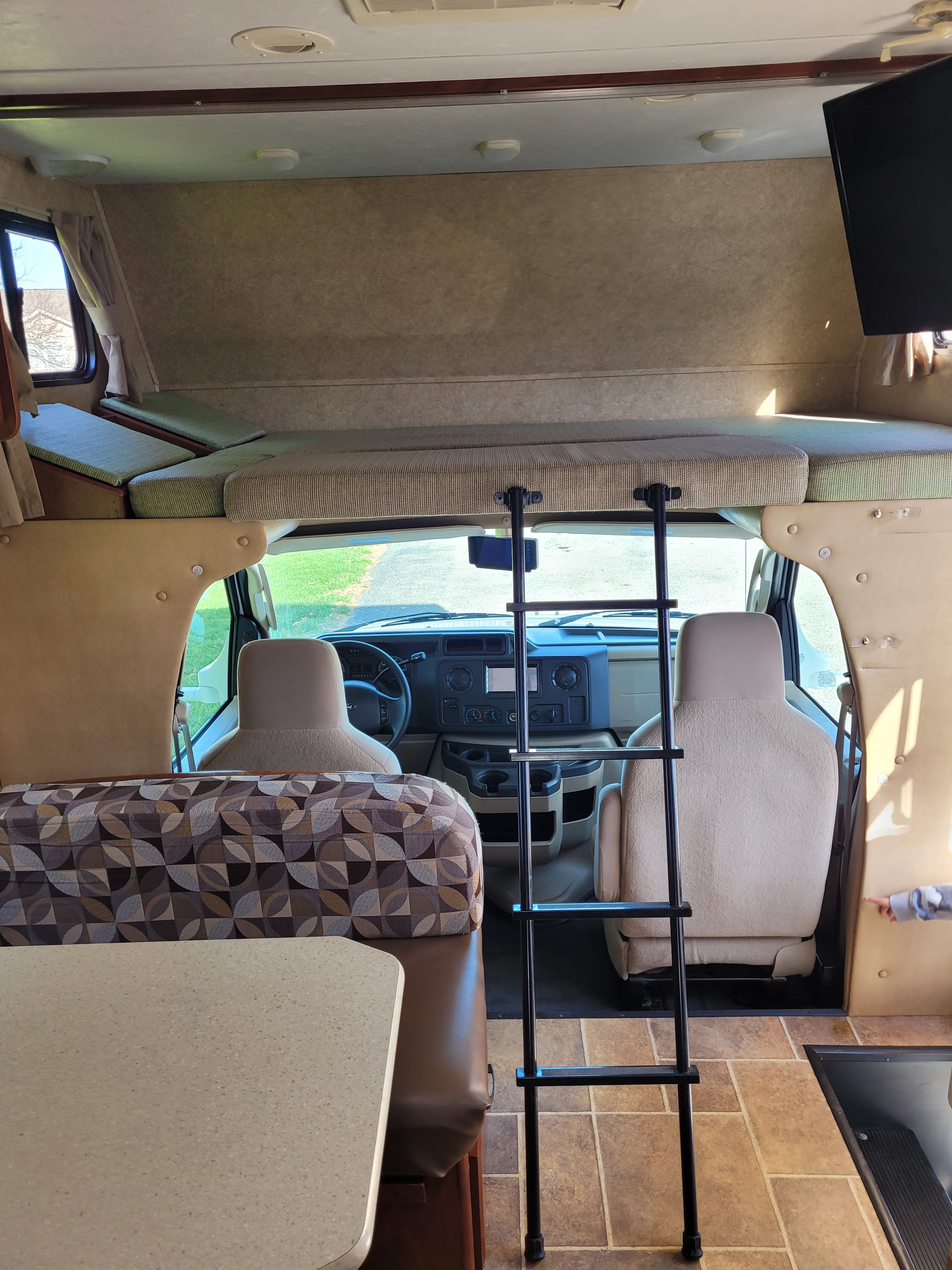 Interior view of an RV rental, showing the cab, overhead bunk with ladder, and dining area.. Forest River Sunseeker 2013