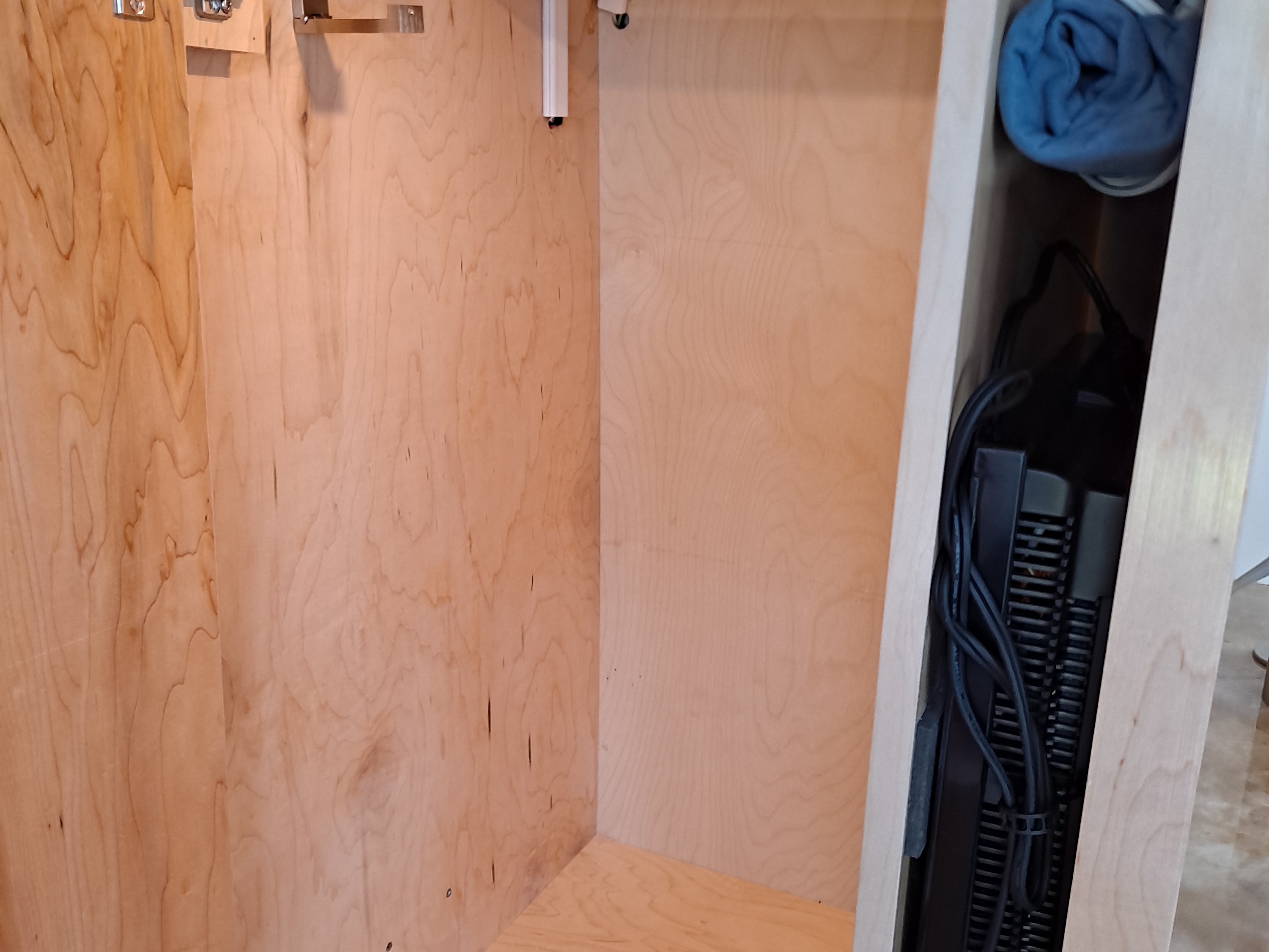 RV rental cabinet interior: light wood, metal hooks, top light strip, and narrow section with black electronics & wires.. Ram ProMaster 3500 2021