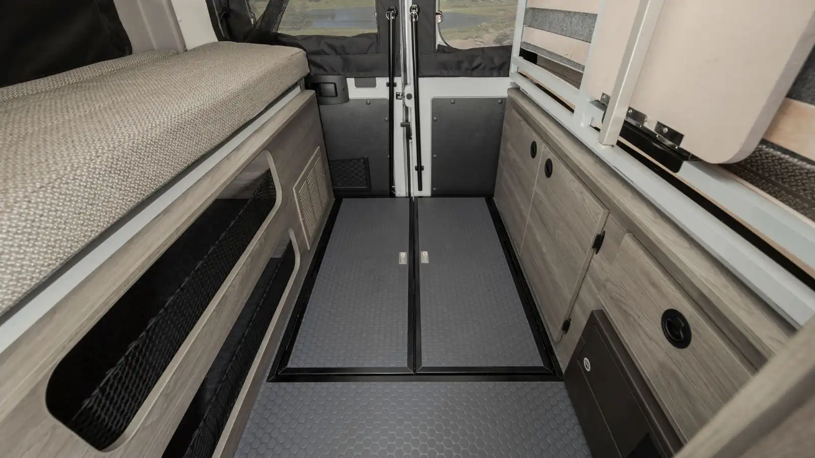 RV rental: Functional camper van interior with a cozy bed, ample storage, and durable floor leading to rear doors.. Winnebago Solis 2022