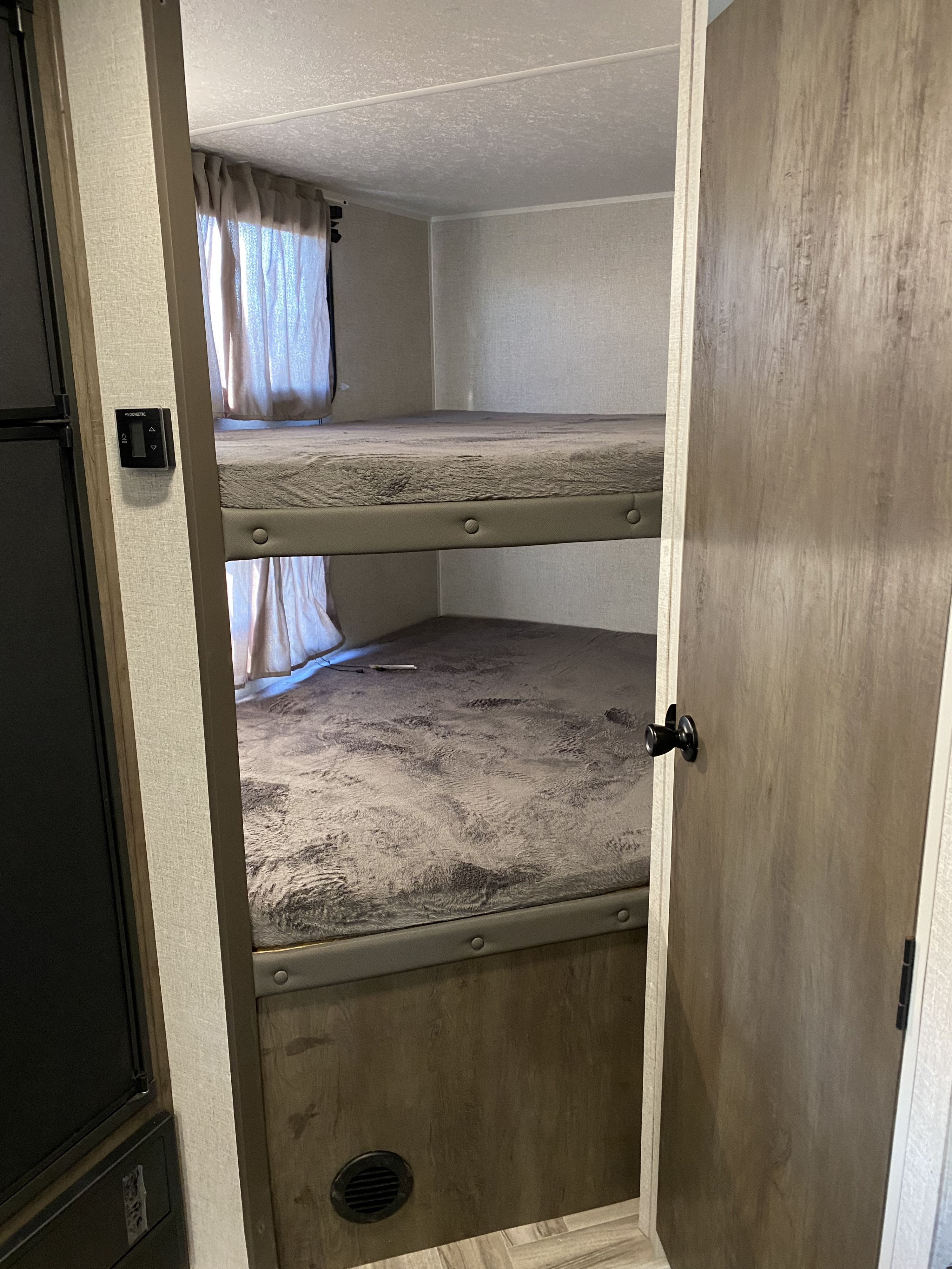 Cozy bunk beds inside an RV rental, offering compact sleeping space. Features a Dometic control panel and curtains.. Forest River Evo 2021