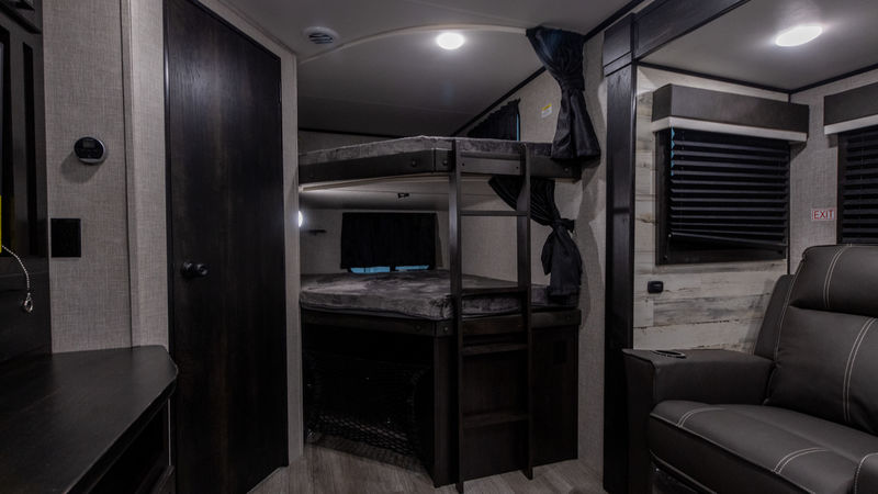 RV rental interior showcasing practical bunk beds, a comfy recliner, and compact living space. Ideal for family travel.. Jayco Jay Feather 2022