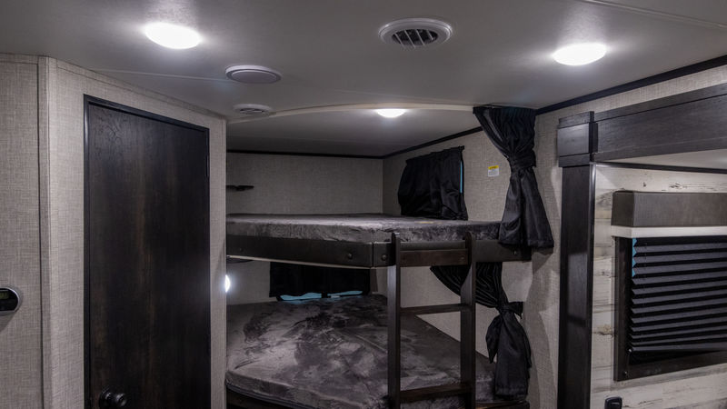 RV rental interior features cozy bunk beds with privacy curtains, dark wood trim, and ample ceiling lights.. Jayco Jay Feather 2022