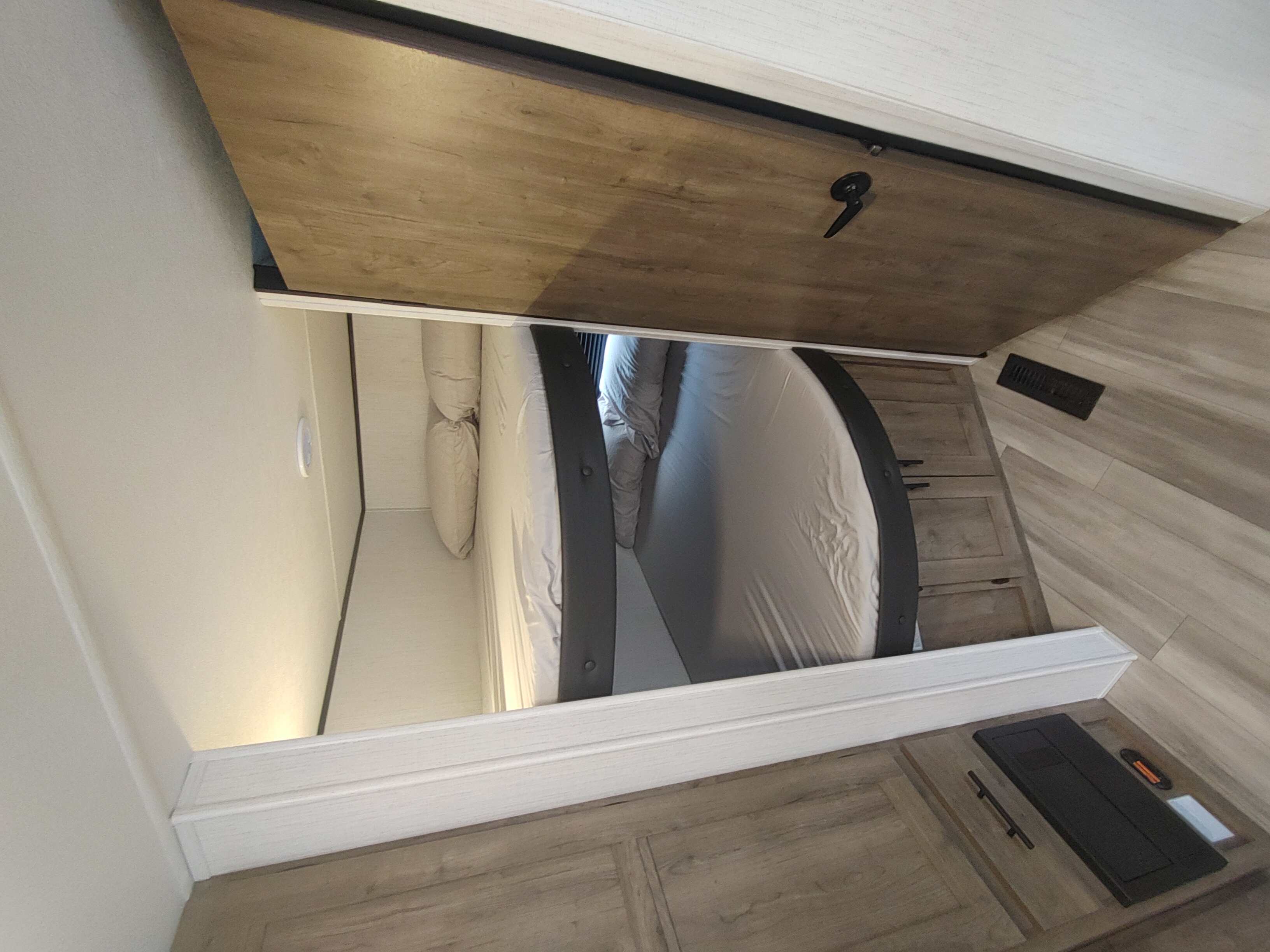 Cozy RV rental bedroom view: Features a modern bed within a slide-out, wood flooring, and a sliding privacy door.. Heartland Pioneer 2022