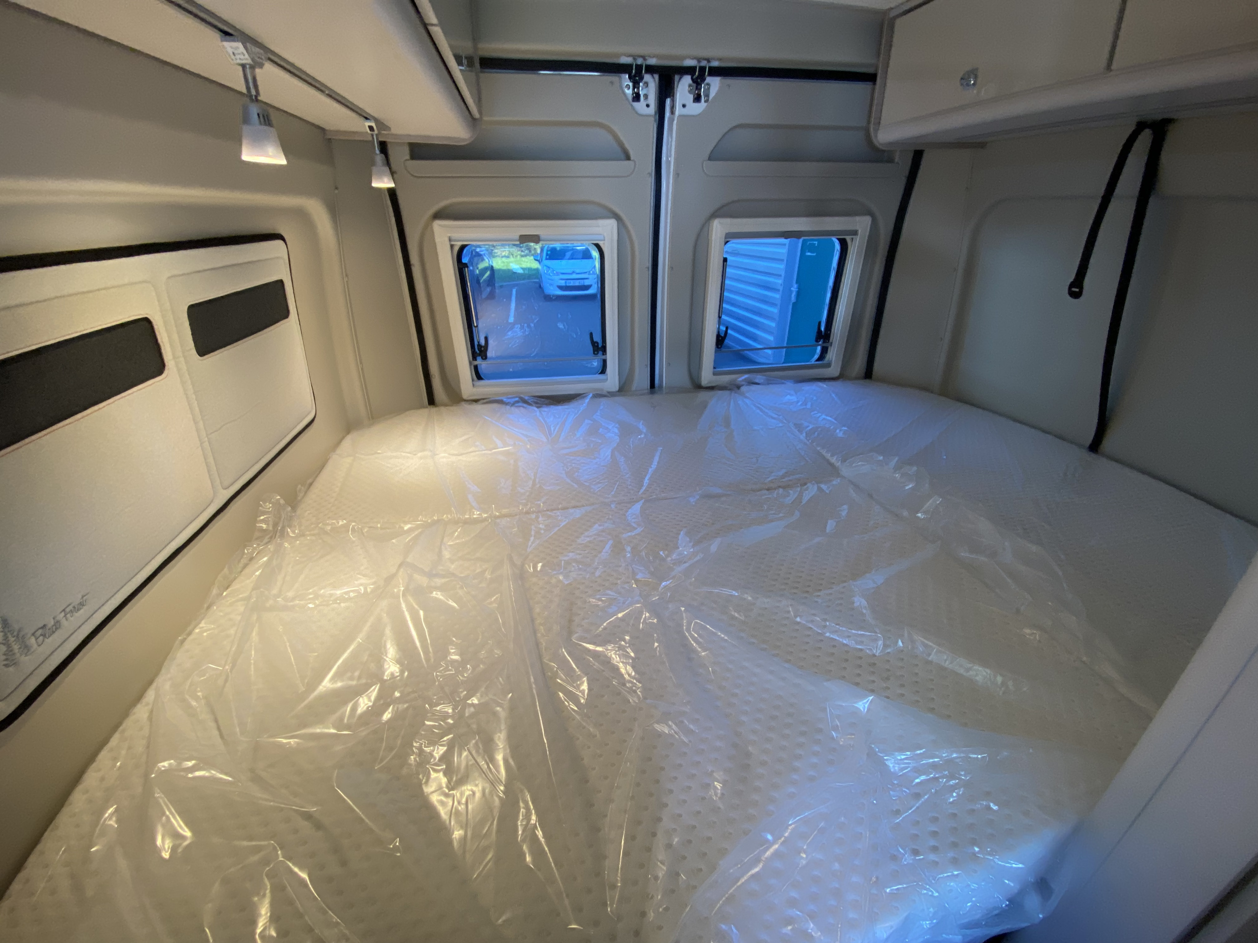 RV rental campervan interior: a spacious sleeping area with new mattress in plastic, rear windows & overhead lights.. Bürstner T600 2022