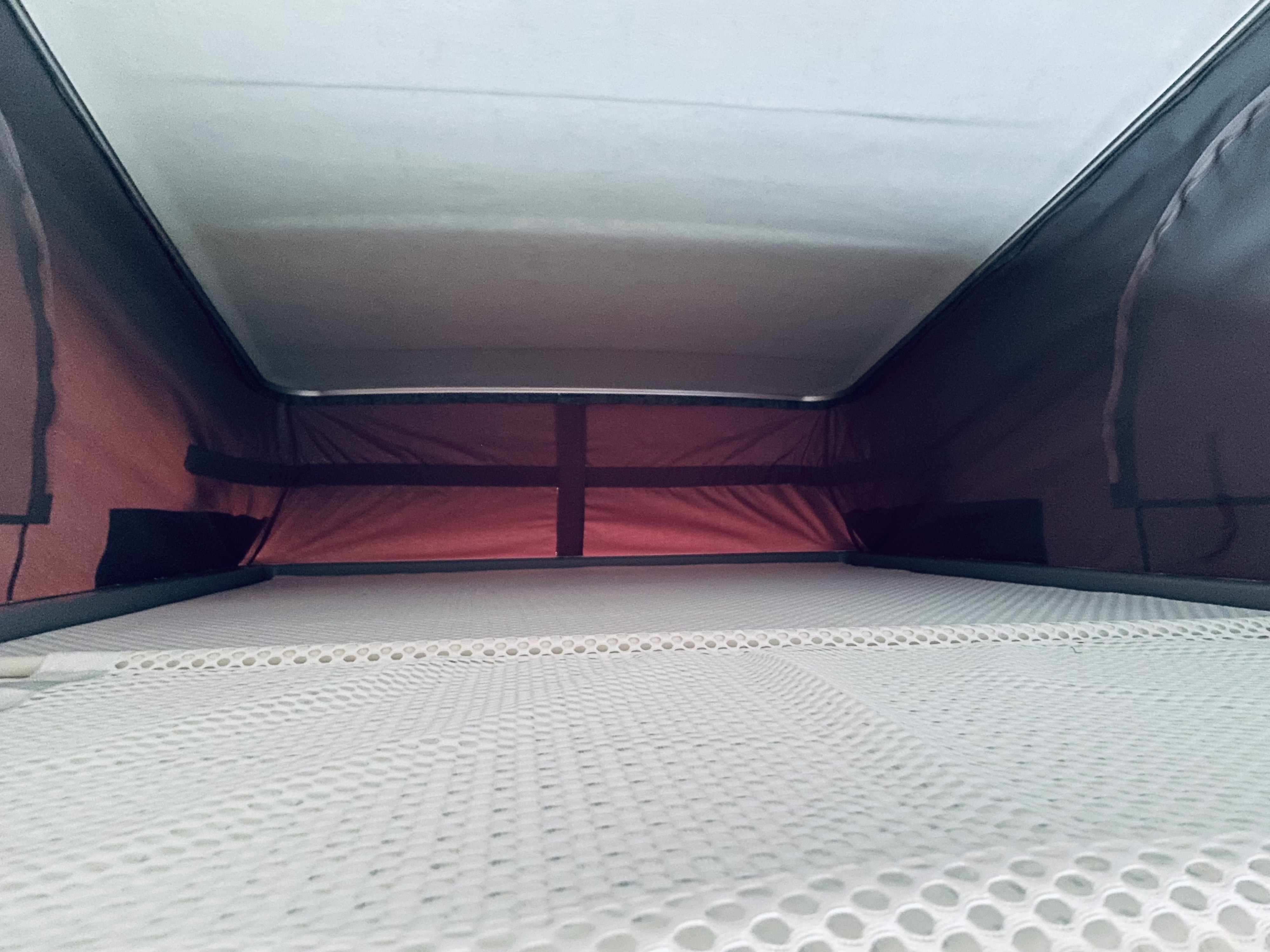 RV rental pop-top interior: a sleeping area with a white mesh mattress and dark fabric walls.. Bürstner T600 2022