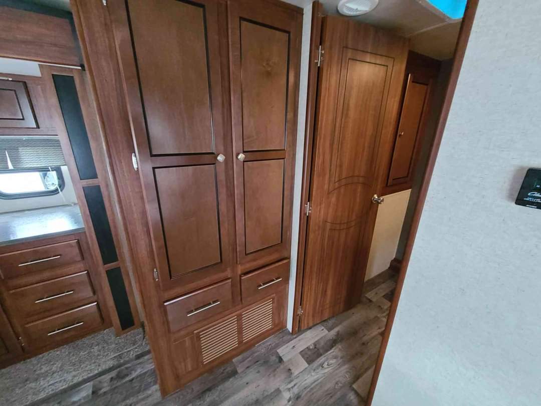 RV rental interior showcasing a large wood wardrobe, ample cabinets, and a connecting door in a compact design.. Heartland RVs Wilderness 2018