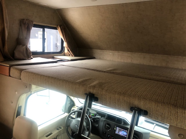 RV rental interior: cozy cab-over bunk bed with mattresses, window, and the driver's area below. Perfect for travel.. Forest River Sunseeker 2016